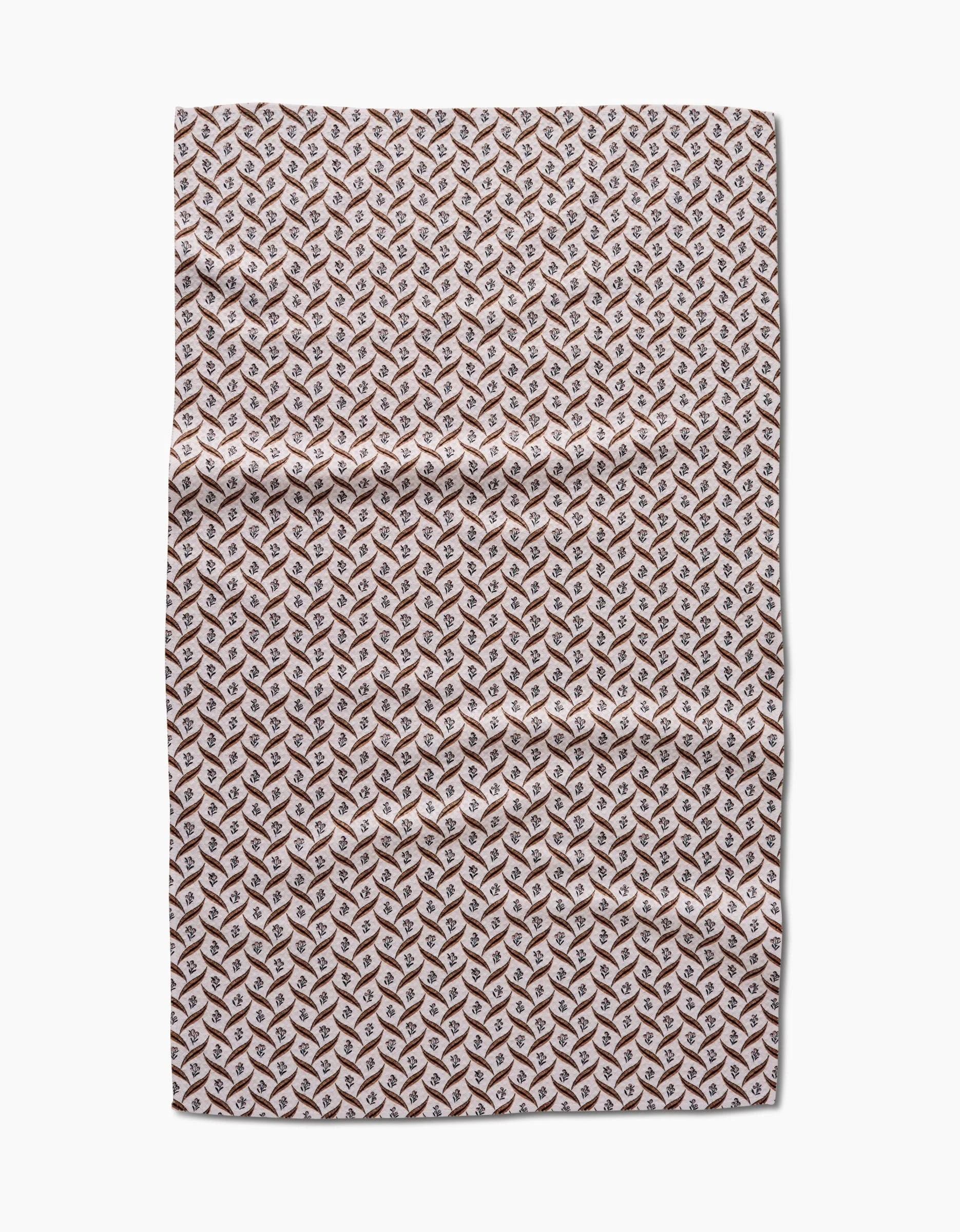 The Hufton Studio Plated Fall Berry Natural tea towel features a repeating geometric pattern in brown, tan, and white that creates a 3D cube effect. Made from Geoweave fabric, the towel is shown flat on a white background with visible creases.