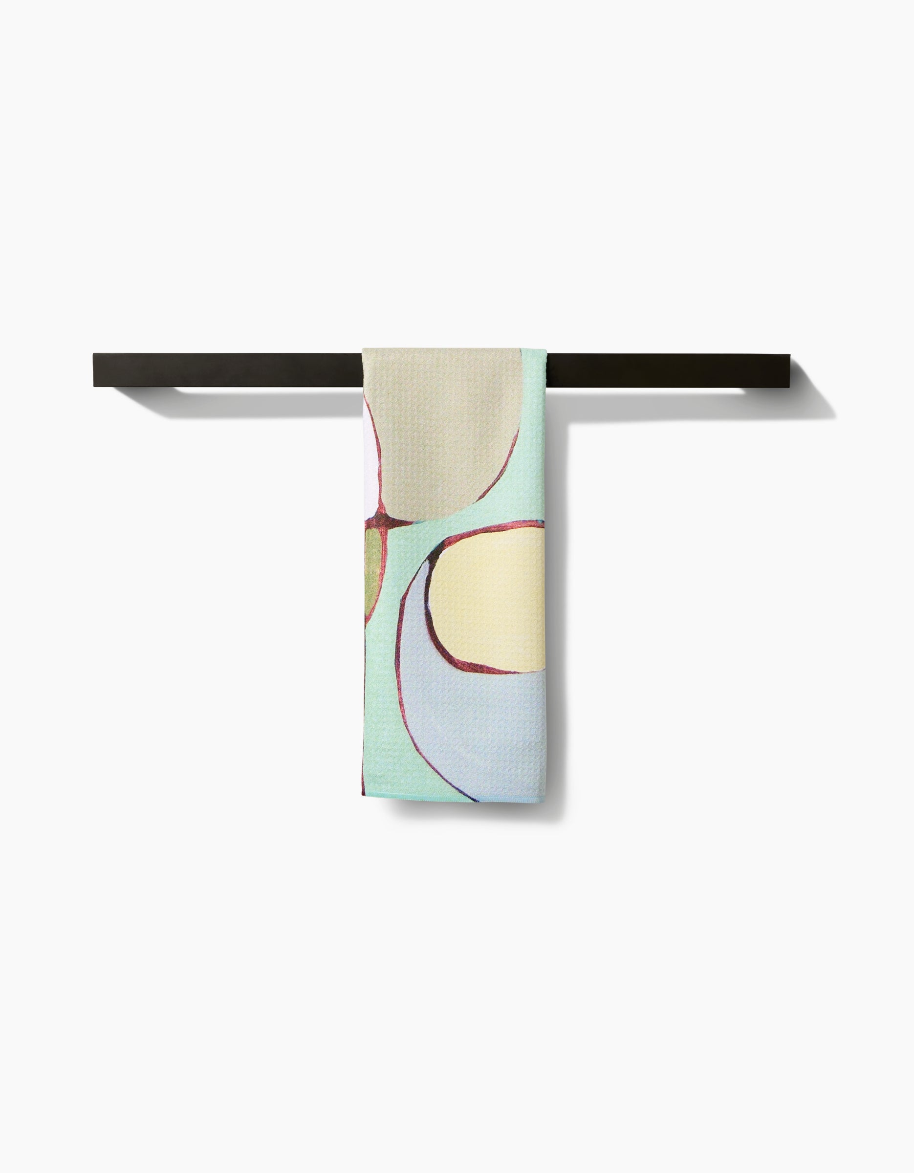 Rachel Austin’s “Poppies on Mint” towel, crafted from ultra-absorbent Geoweave and featuring abstract poppy designs in pastel tones, hangs neatly on a black towel bar against a plain white background.