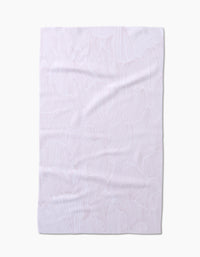 The Geometry Posh Petals Blushed Bergamot kitchen towel is shown flat on a white background, its subtle textured leaf-like pattern and slight wrinkles visible. Made from recycled materials for an eco-friendly touch.