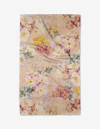 The Primroses tea towel by Pascale Dilger features pink, yellow, and white flowers with green leaves on a light beige background. Made from recycled materials, the slightly wrinkled fabric is shown on a plain white surface.