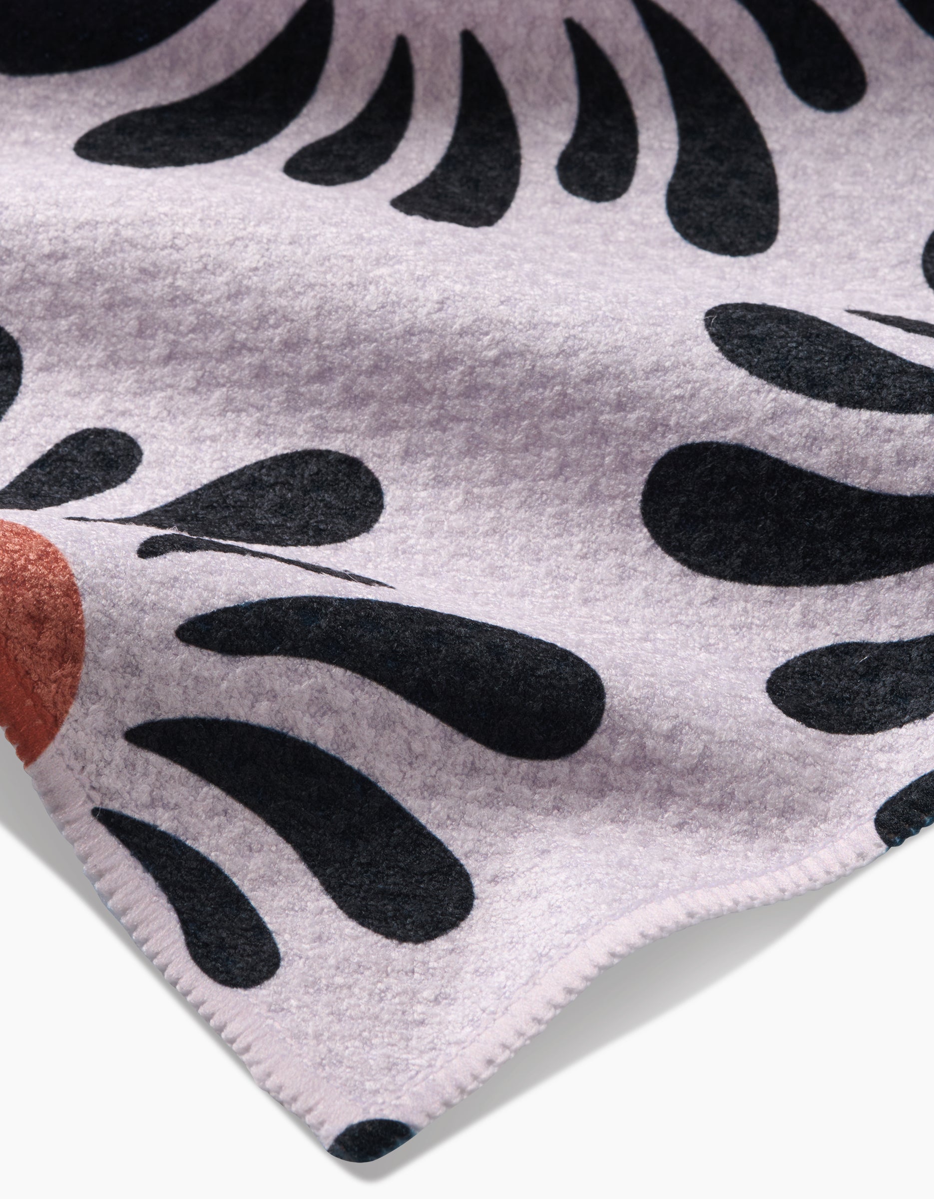 A close-up of the Realm Refillery Tea Towel by Realm Refillery, showing its light lavender background, bold black abstract shapes, small rust-colored semicircle, eco-friendly Geoweave fabric, and visible stitched edge.