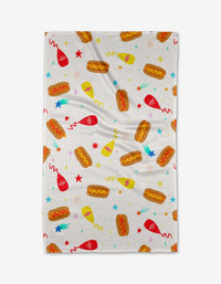 The Rocket Relish tea towel by Vaishali Design Studio features playful hot dogs, ketchup and mustard bottles, plus colorful stars on a white background—perfect for adding fun to your kitchen.