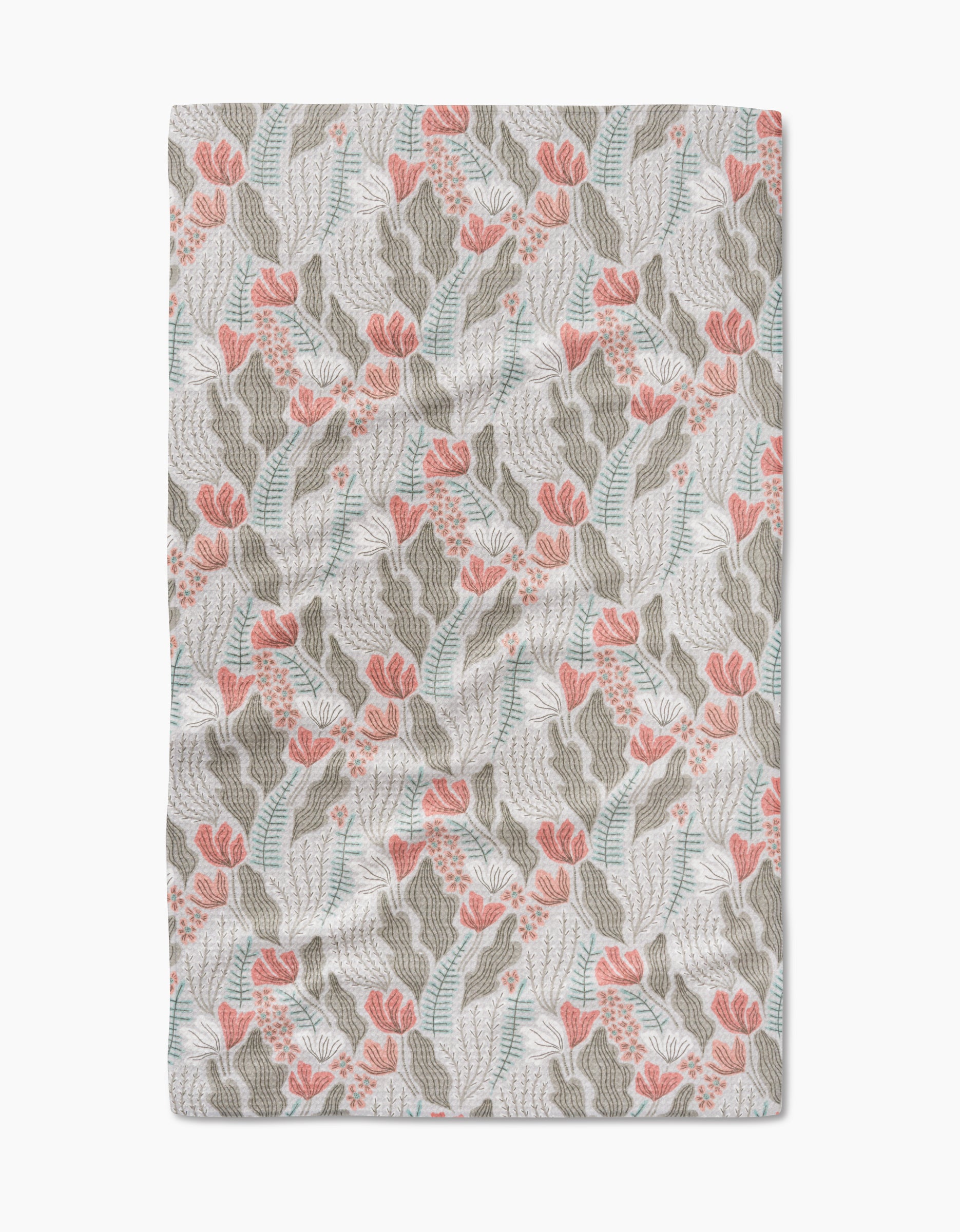 The Rollie blanket by Amy MacCready features a botanical pattern with pink flowers, green leaves, and blue accents on a white background, inspired by Geometry House Tea Towels. Its slightly wrinkled fabric adds extra coziness.