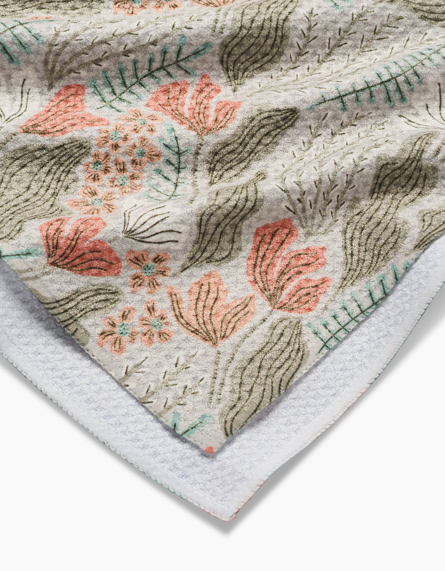 A close-up of the soft Rollie Geoweave fabric by Amy MacCready displays a floral and leaf pattern in pink, green, and orange tones with a textured surface and white edge, highlighting its signature tea towel quality.
