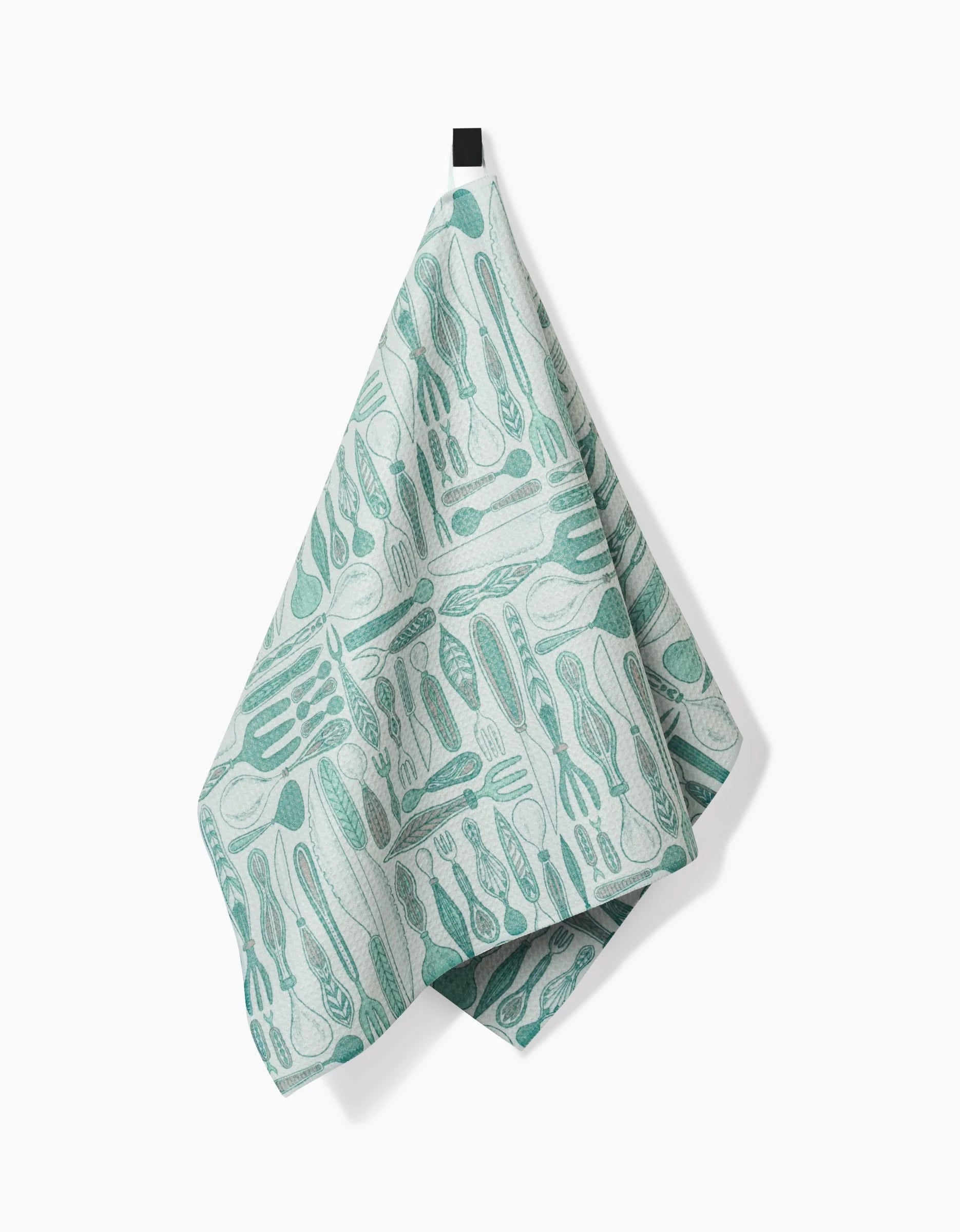 The Romy kitchen towel by Amy MacCready, in light blue and white with a kitchen utensil pattern, eco-friendly and hanging from a black loop, is displayed against a plain white background.
