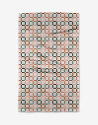 The Russet Crossroads blanket by Charlie Rowan Designs features a geometric checkerboard pattern in pink, brown, gray, and white Geoweave fabric, with interlocking shapes for a modern look—reminiscent of the cozy Geometry House Tea Towel. Slightly wrinkled.
