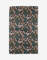 The Charlie Rowan Designs Russet Park Lane Tea Towel features a dark green background with a lively botanical pattern of orange and pink birds, pink flowers, and green leaves. Made from eco-friendly Geoweave™ fabric with recycled materials.