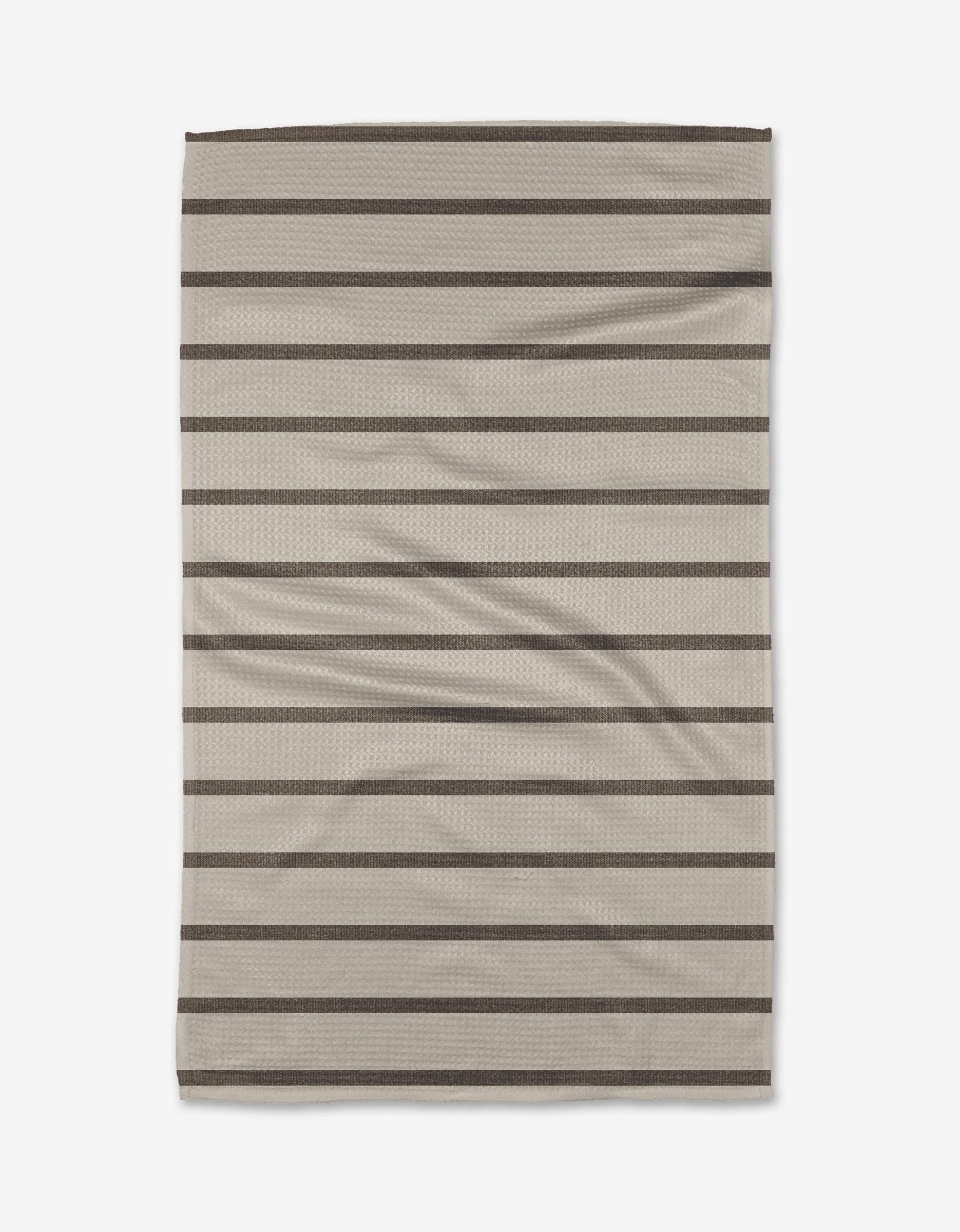 The Salt Air Stripe dish towel by Jenny Keller features a beige rectangular design with horizontal dark brown stripes. Soft and slightly wrinkled, it’s perfect for everyday kitchen use.