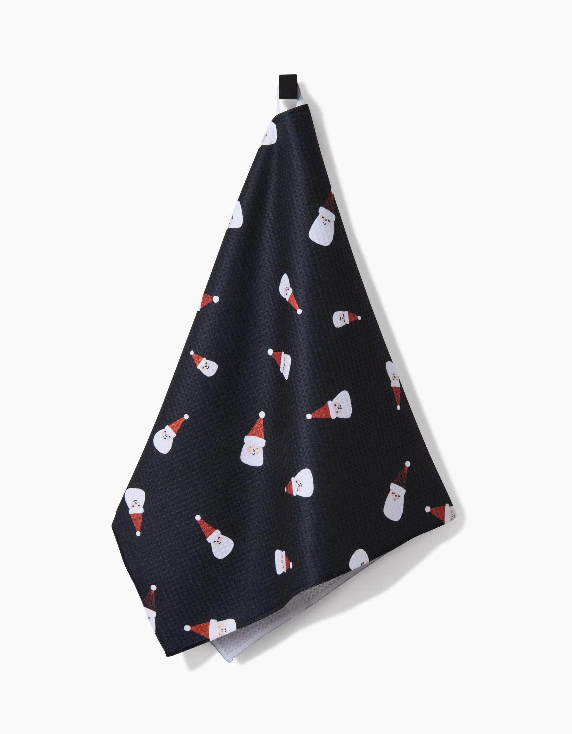 The Coit Creative Santa Faces tea towel, ultra-absorbent and dark with red-hatted Santa Claus faces, hangs from a black loop against a white background.