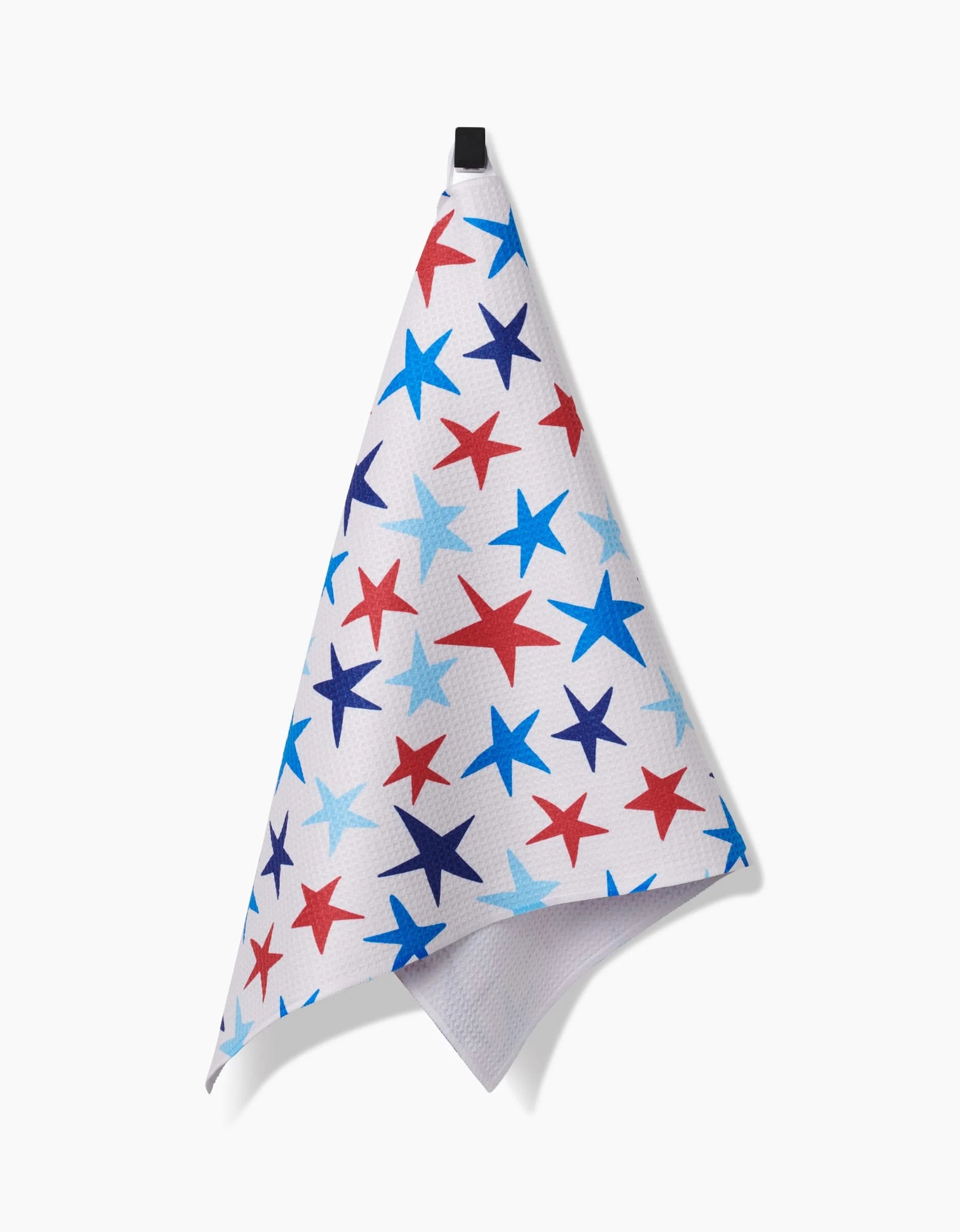 The Mindfulnice Seeing Stars tea towel, made from soft Geoweave™ fabric, features red, light blue, and dark blue stars on white and hangs from a black loop against a plain white background.