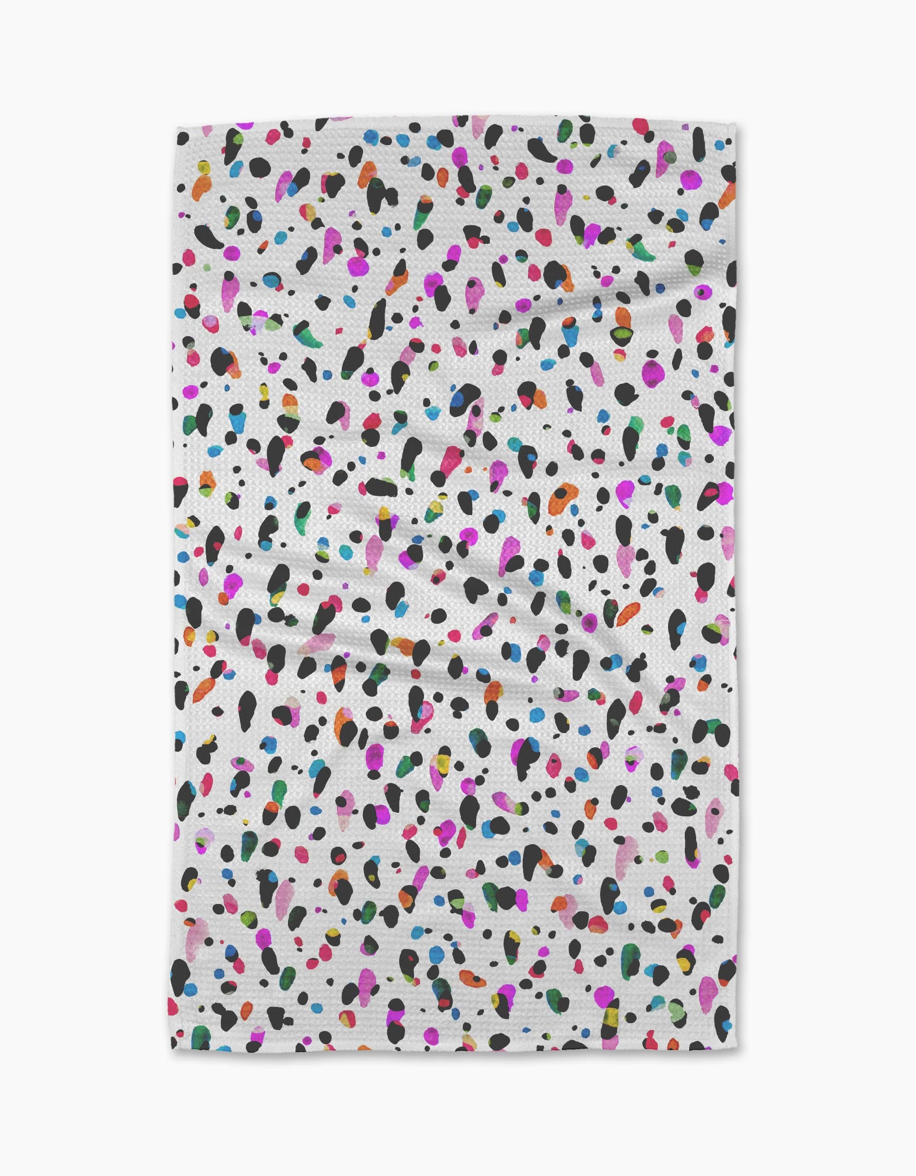 The Spot tea towel by Rachel Parker features a white, ultra-absorbent fabric with scattered black, pink, blue, orange, green, and purple spots. Its plain background highlights the lively pattern on this slightly wrinkled kitchen accessory.
