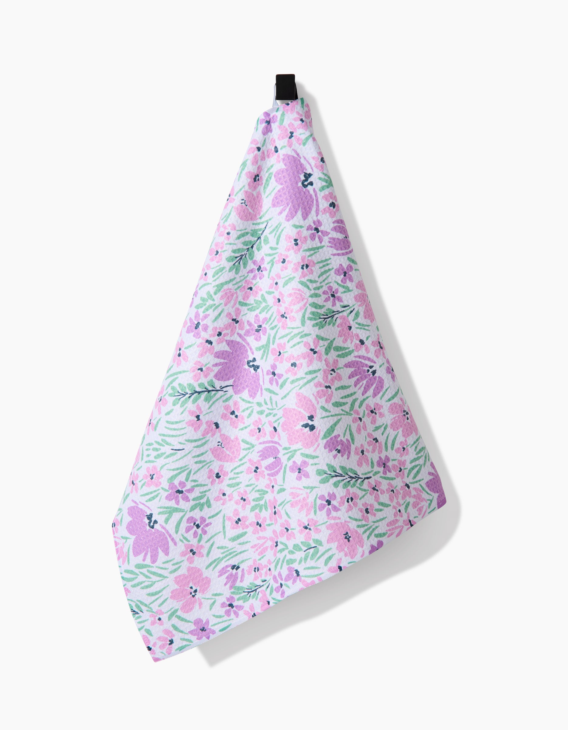 The Hufton Studio Spring Fleur Blooms tea towel features a pink, purple, and green floral pattern on white, made from recycled materials and shown on a white surface.