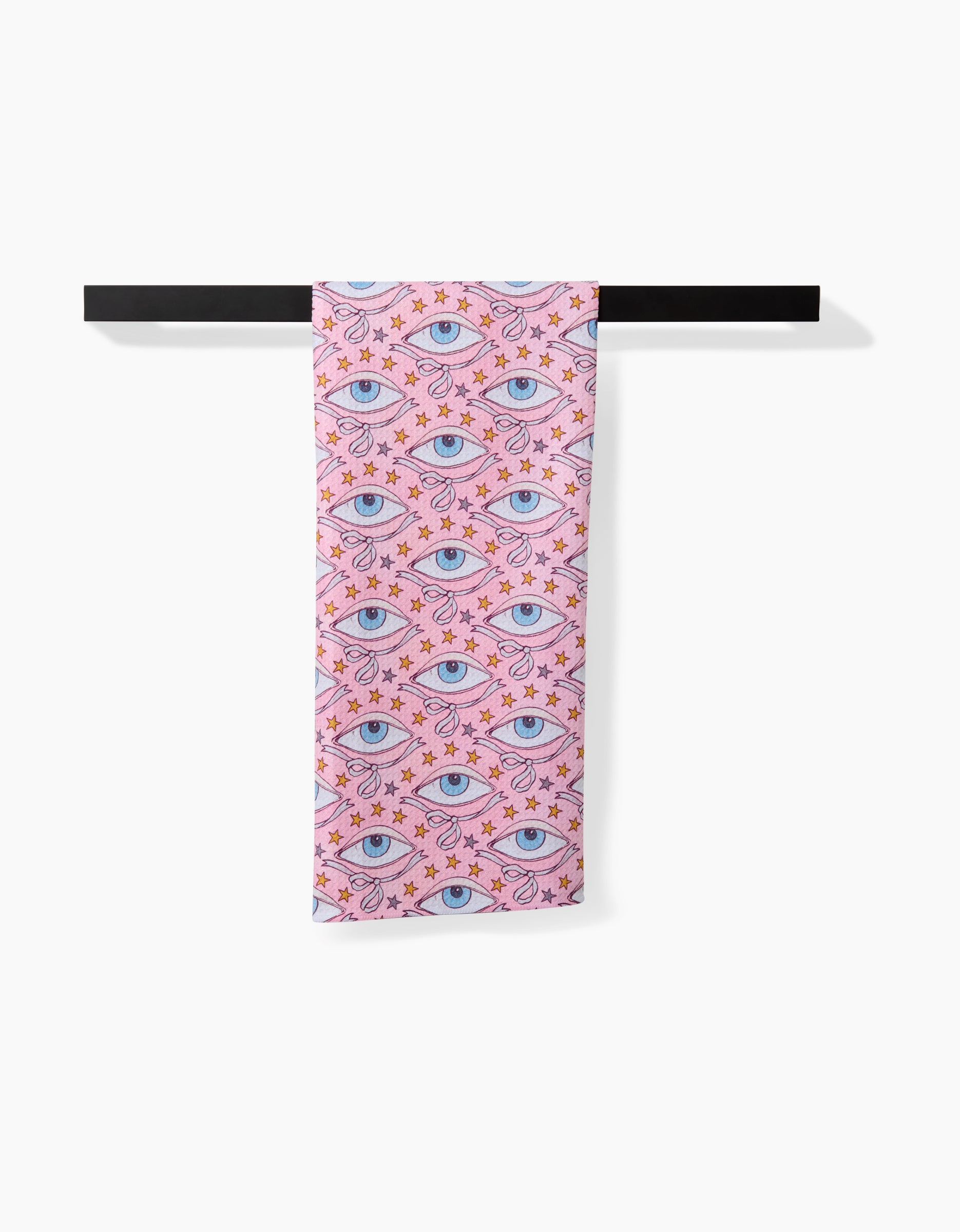 The Stella scarf by Maayan Alper-Swan, made from recycled materials, features blue eyes and orange stars on pink fabric. It is draped over a black rod with a white background.