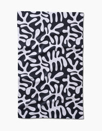 The Sunset tea towel by Marina Solodka features a rectangular, ultra-absorbent Geoweave™ fabric with a black background and abstract white, amoeba-like patterns.