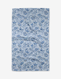 The “Tea Set Blossoms” kitchen towel by Sara Mari is a rectangular, recycled piece featuring a blue floral pattern with assorted flowers and leaves on a light background, shown laid flat against a white surface.