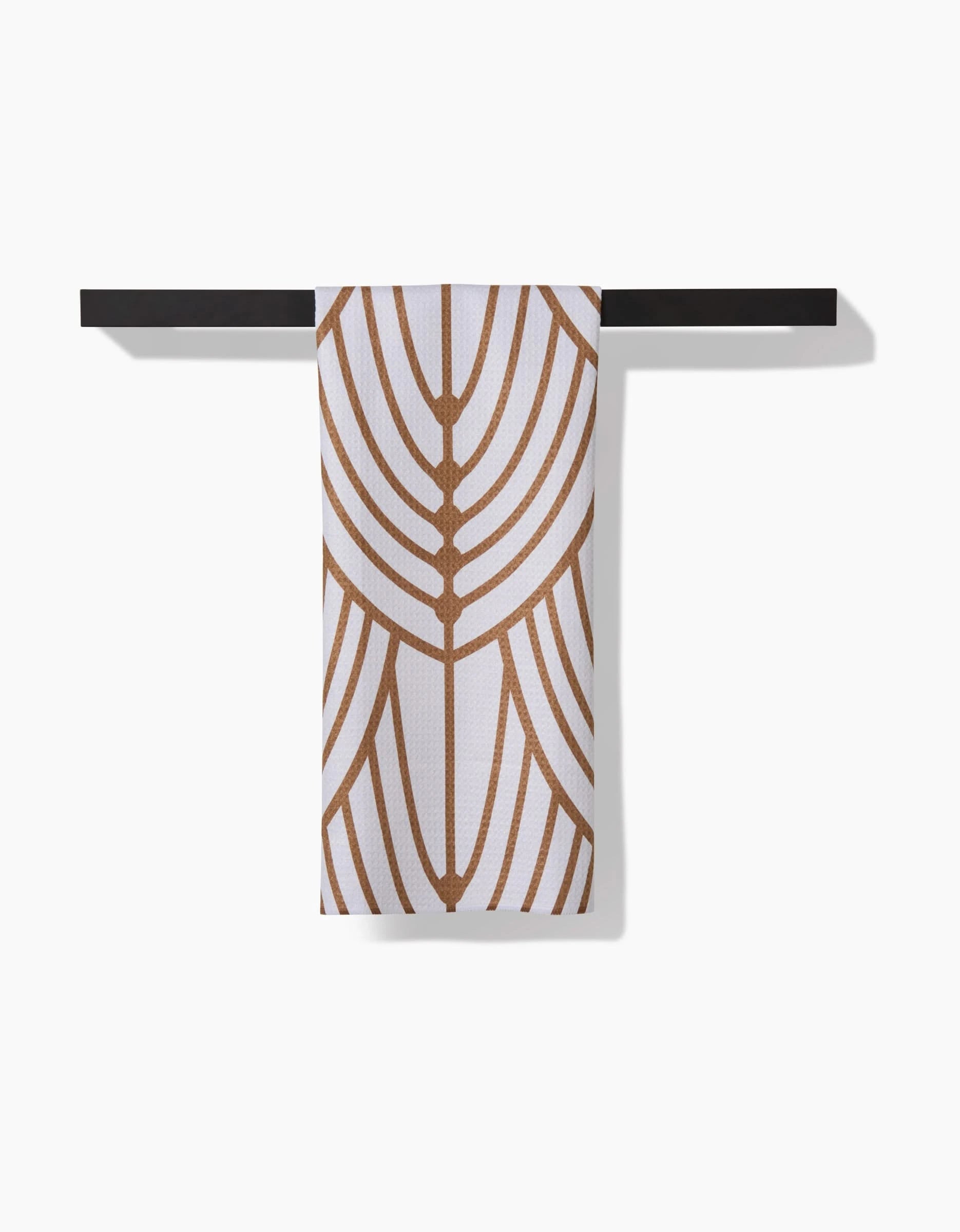 An Amy MacCready Tiffany Tea Towel with a geometric brown pattern hangs neatly on a simple black towel bar against a white background.