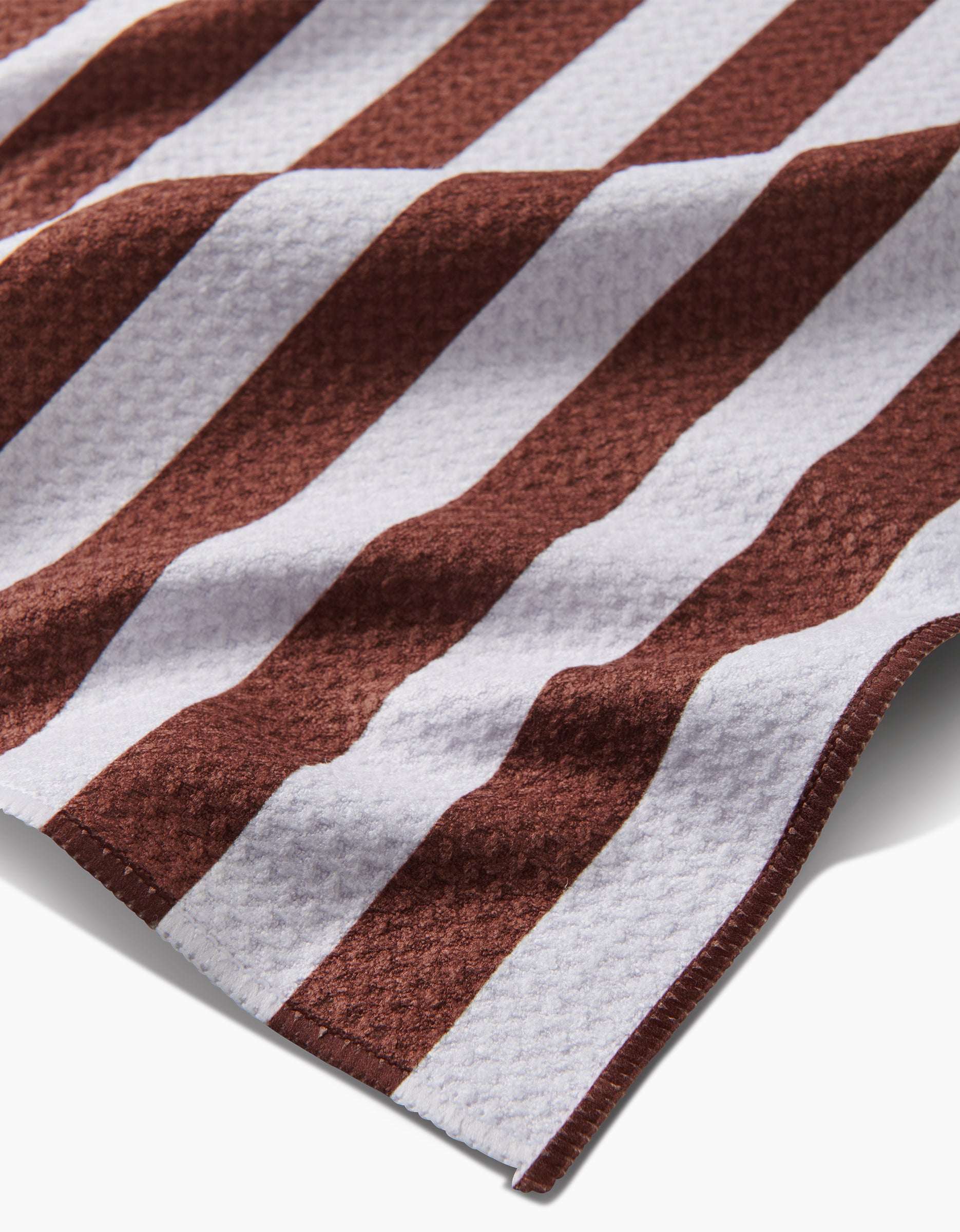 A close-up of the Kailee Wright Toni Stripe Geoweave™ tea towel, featuring alternating white and brown textured stripes, shown slightly rumpled at an angle.