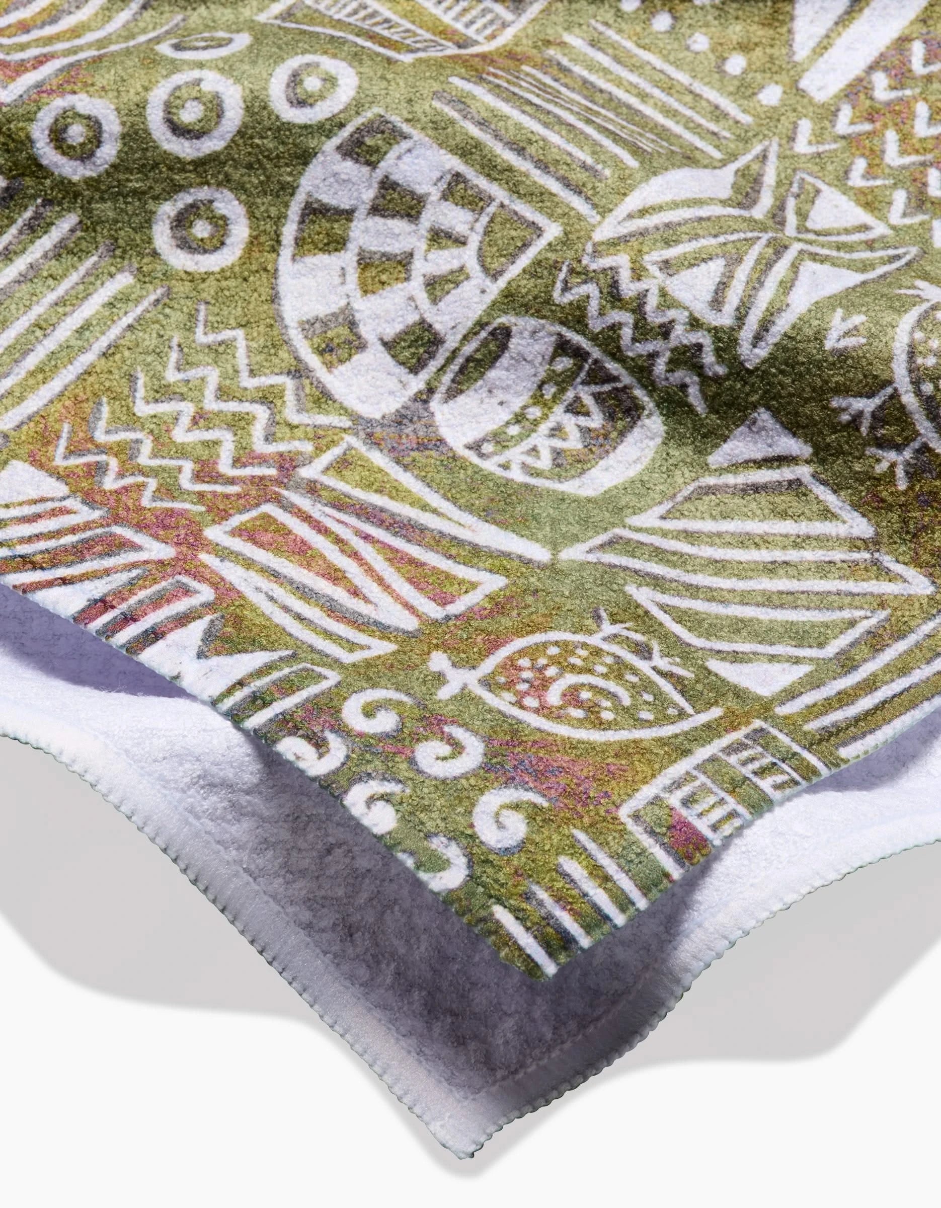 A close-up of the Tribal Symbols tea towel by Taryn Brennan, made with Geoweave fabric and featuring colorful abstract tribal-style patterns in white, yellow, and green with a soft white border.