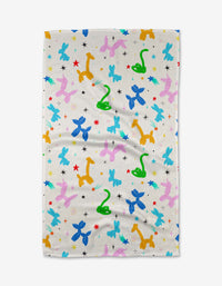 The Vaishali Design Studio Twisties towel is ultra-absorbent and white, featuring a playful pattern of balloon animals—blue and pink dogs, yellow giraffes, green snakes—and red, blue, and black stars. Perfect as a fun tea towel for your kitchen.