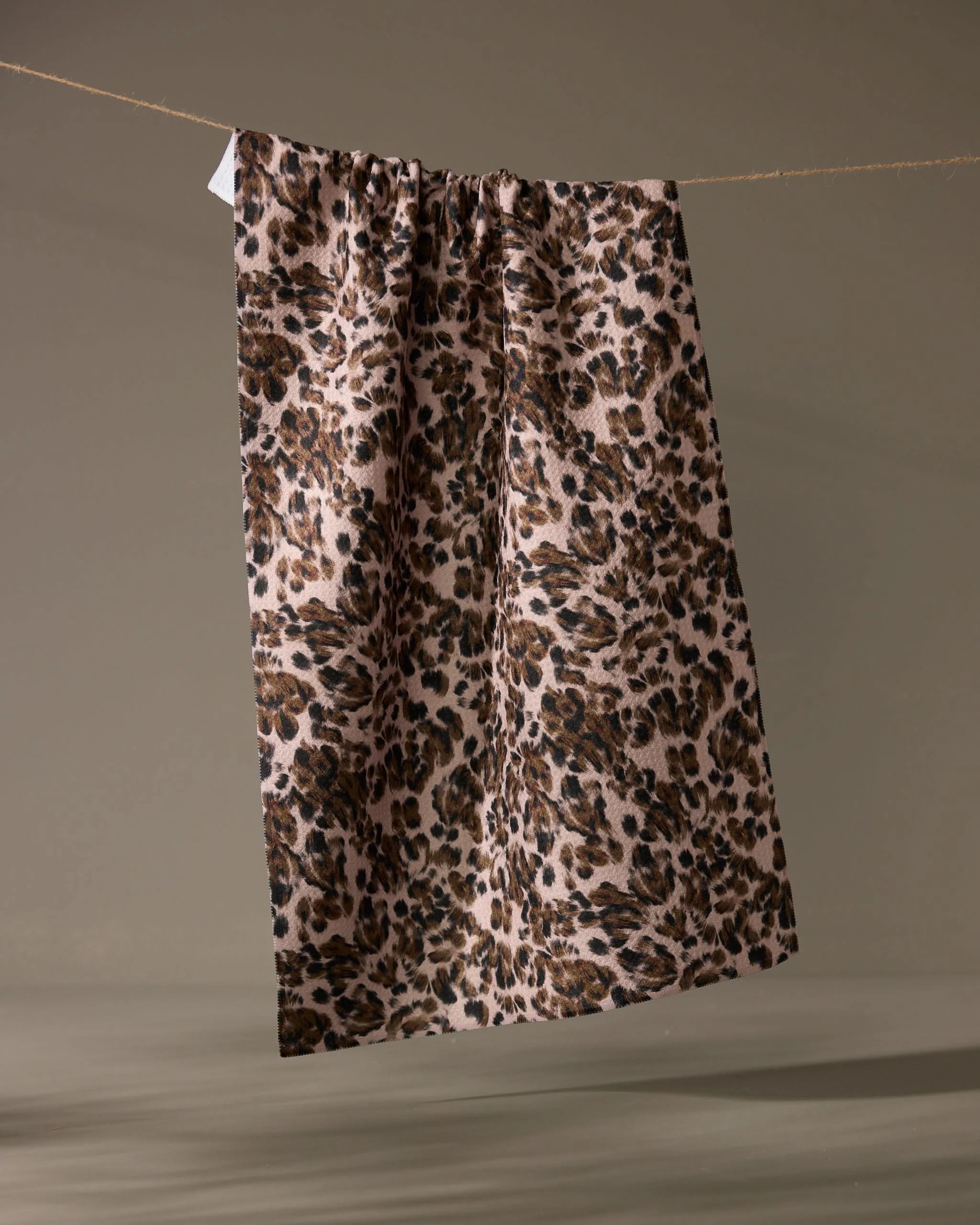 The Geometry Umber dish towel features a brown, black, and beige leopard print on rectangular fabric—an absorbent and stylish addition to any kitchen.