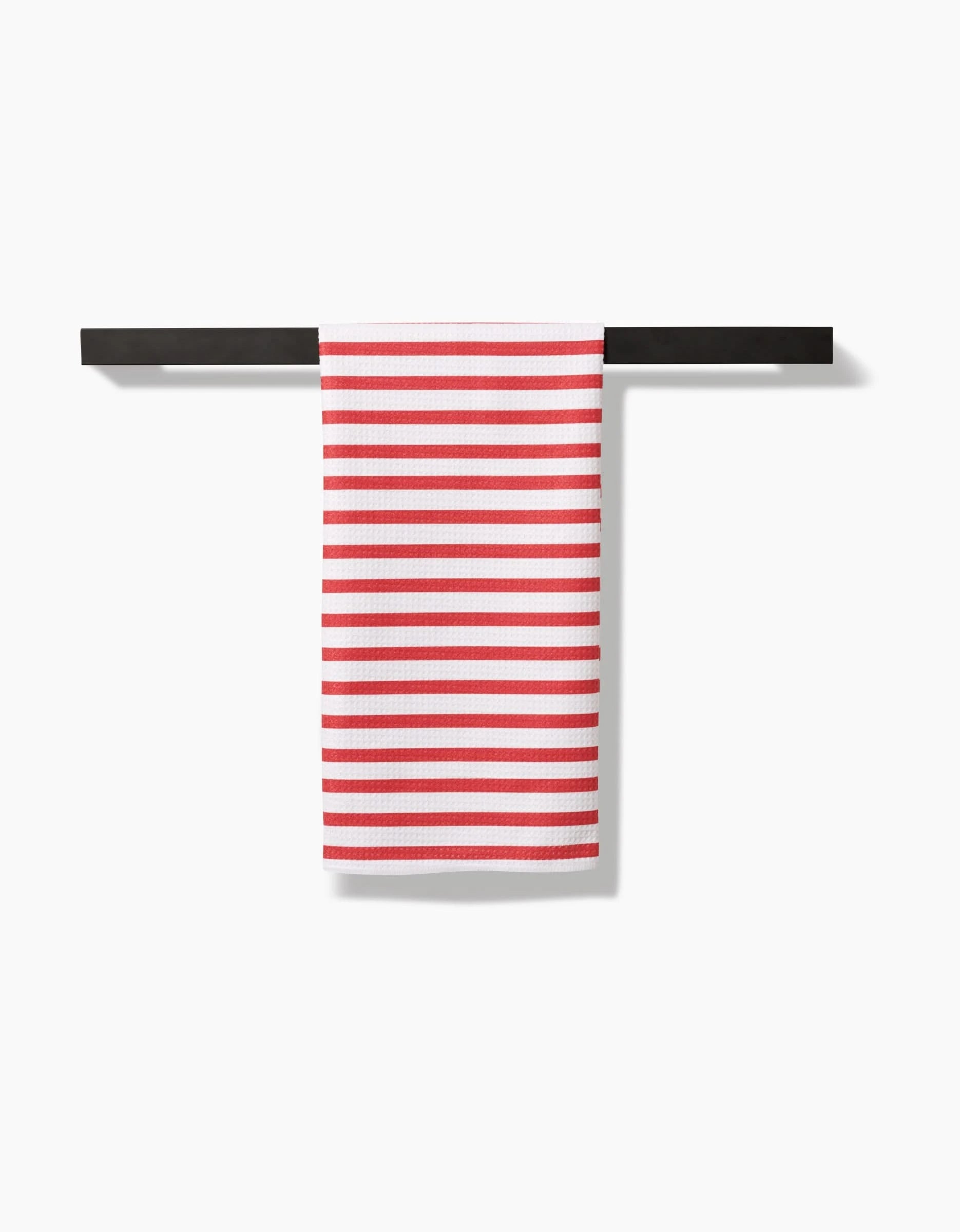 The Mindfulnice USA Stripes tea towel, crafted from Geoweave fabric for enhanced absorbency and durability, features evenly spaced horizontal red stripes on white and hangs neatly on a black towel bar against a white background.