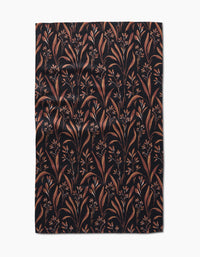 The Hufton Studio Vintage Grass Black tea towel is rectangular, made from Geoweave fabric, and features a black background with brown and tan leafy branches and small flowers, shown flat with slight wrinkles.