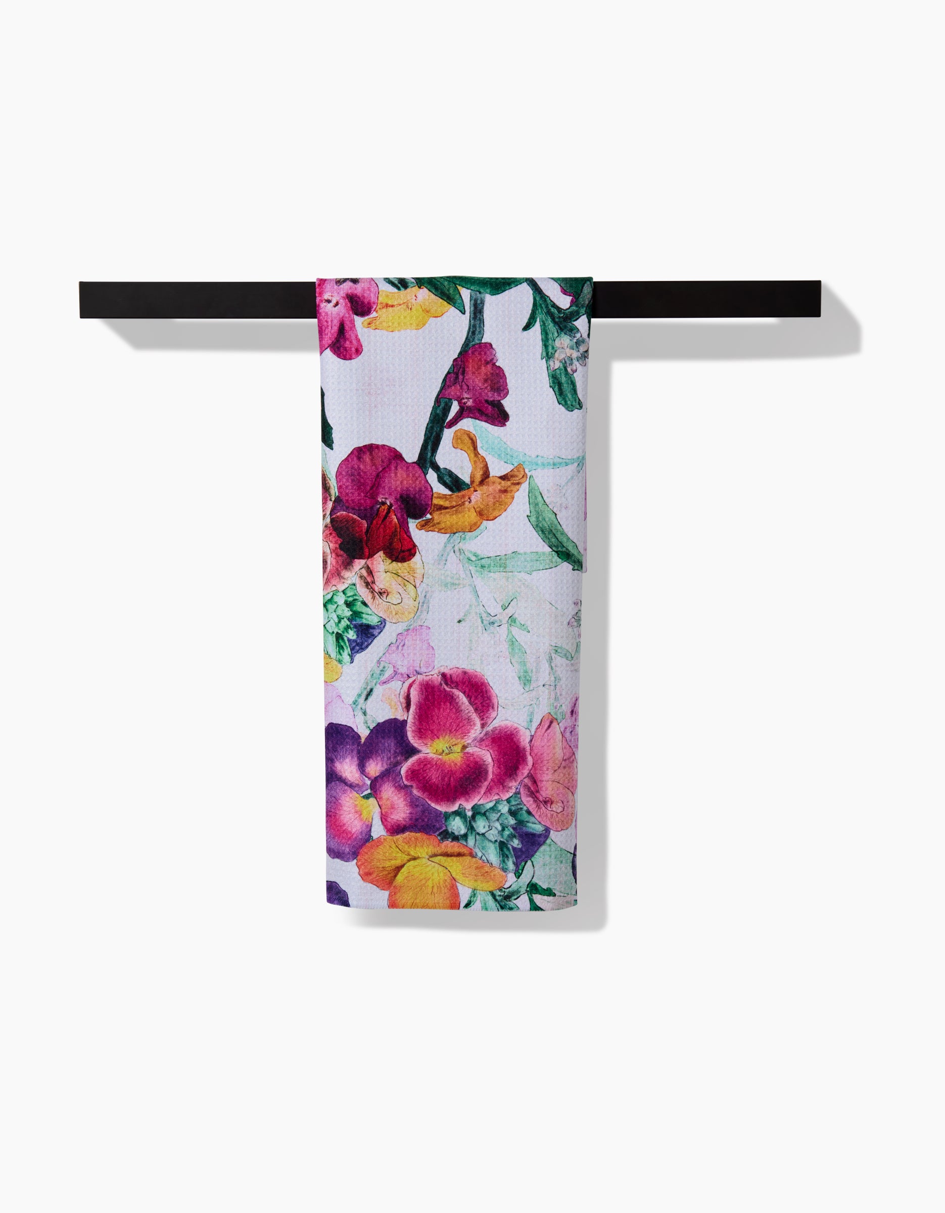 The Pascale Dilger Wallflower towel, featuring a vibrant floral pattern and made from ultra-absorbent Geoweave fabric, hangs on a black towel bar against a white background.