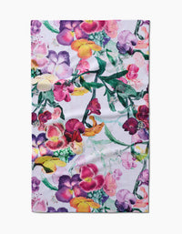 The Wallflower towel by Pascale Dilger features a vibrant floral pattern in purple, pink, yellow, and green on ultra-absorbent Geoweave fabric with a white background.