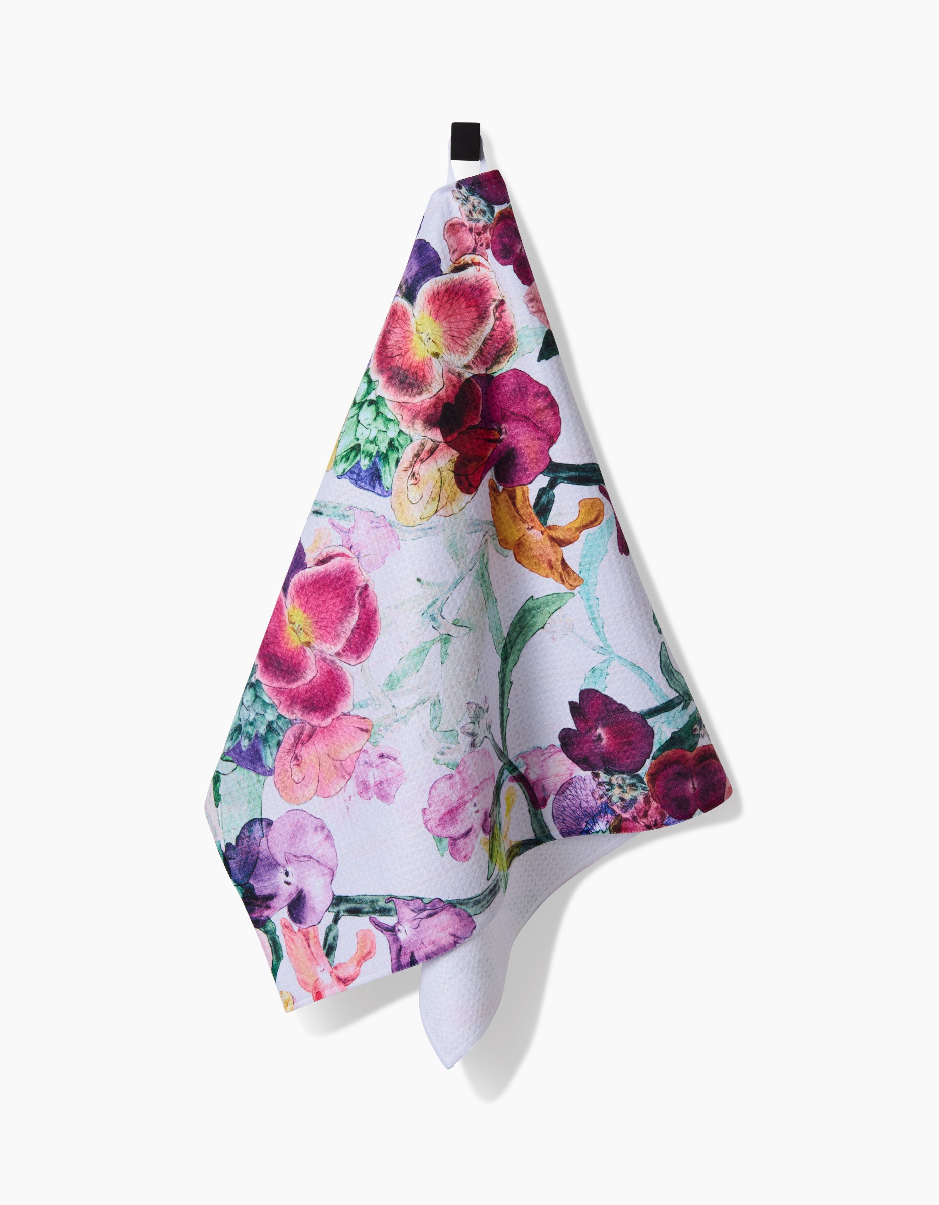 The Wallflower towel by Pascale Dilger features a colorful floral pattern with pink, purple, and yellow flowers on white Geoweave fabric, hanging from a black loop for exceptional absorbency and style.