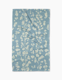 The Geometry Lilou Light Blue tea towel features a delicate white floral pattern on a light blue, ultra-absorbent textured fabric with subtle wrinkles for added charm.