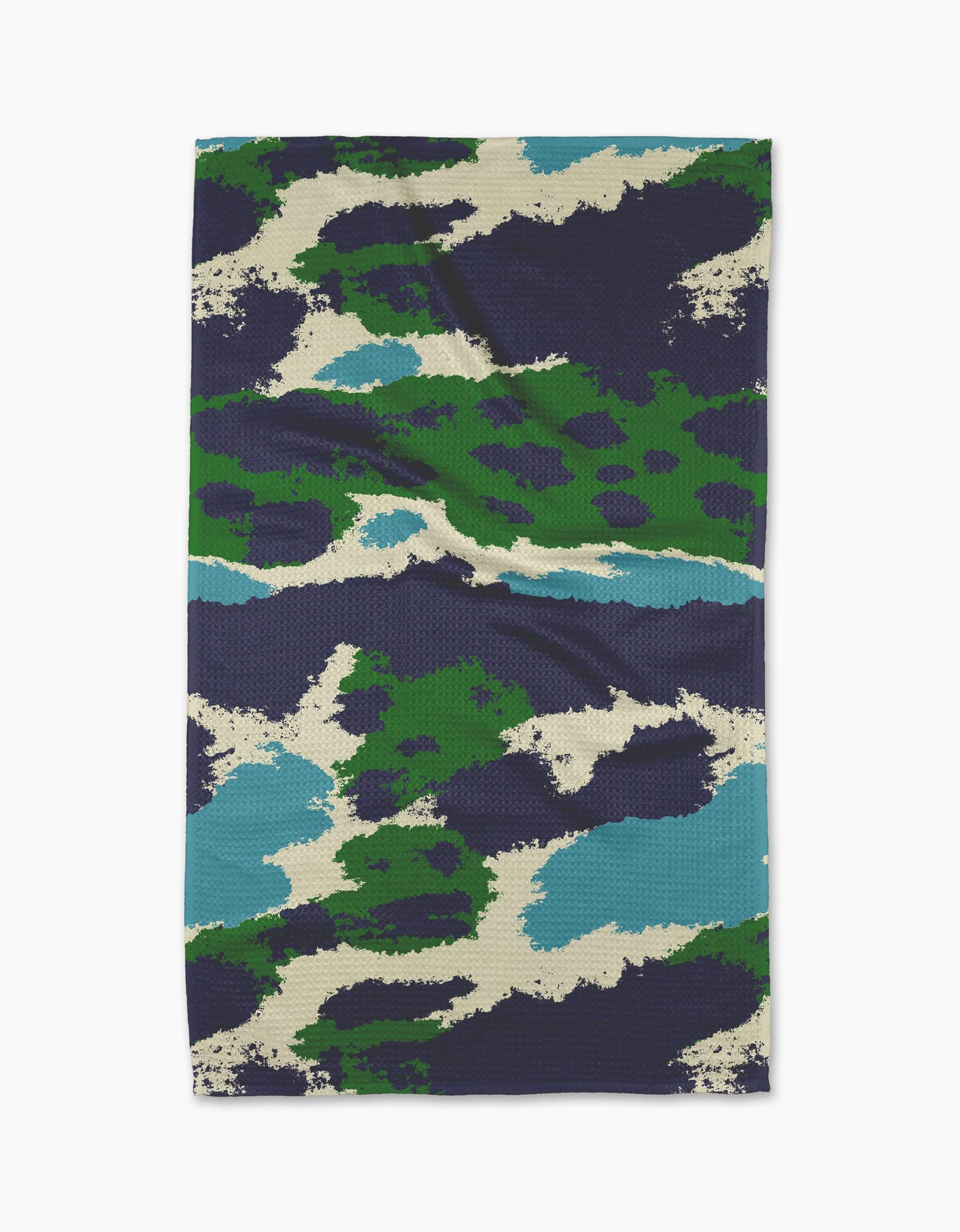 The Geometry Tarn Green kitchen towel features a rectangular shape with a dark blue, green, teal, cream, and black camouflage pattern of abstract shapes. The slightly wrinkled fabric is shown flat, highlighting its textured design.