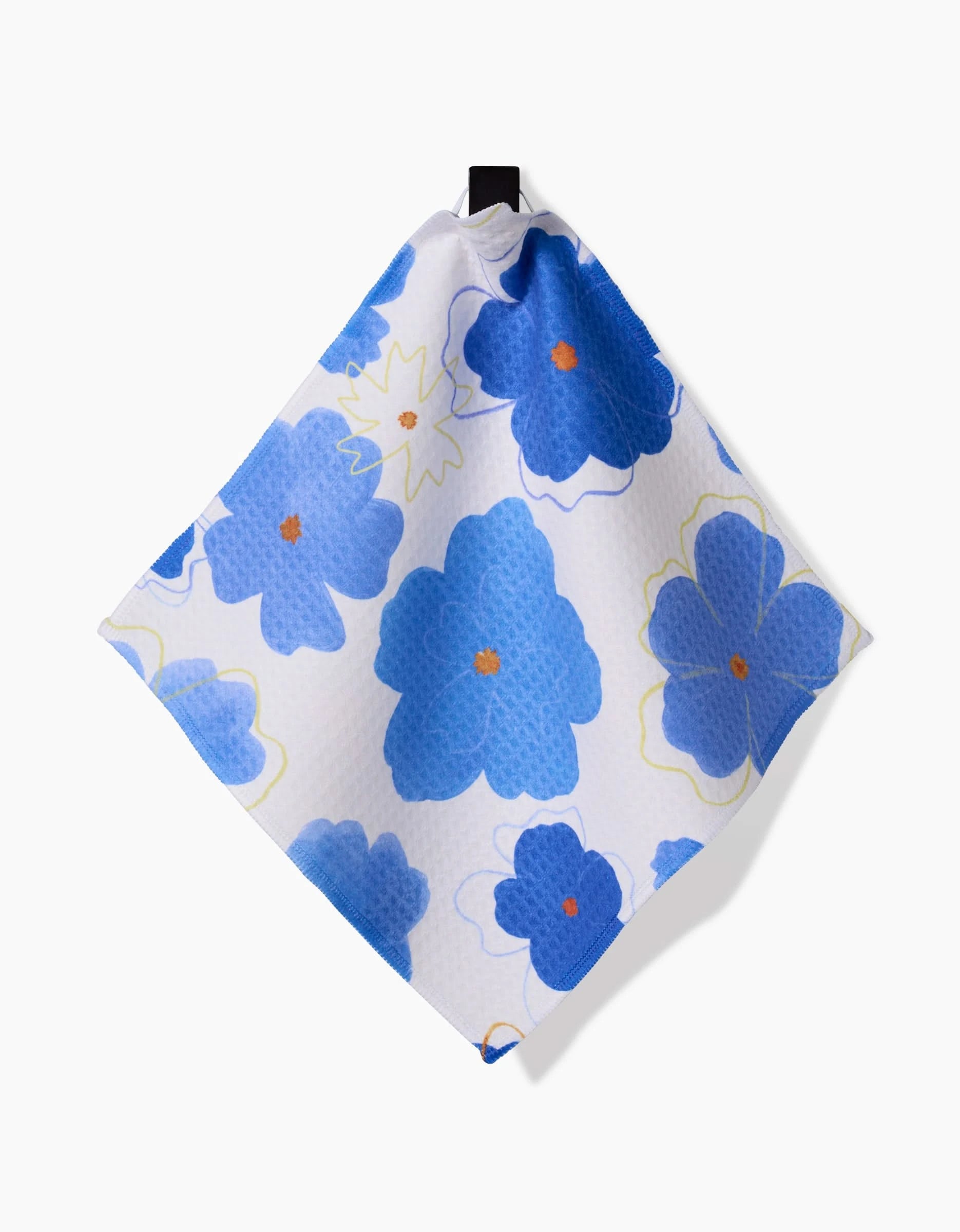 The Blue Blossoms Luxe Washcloth by Elana Gabrielle, a square white cloth with large blue flowers and orange centers, made ultra-absorbent with Geoweave technology, hangs from a black loop against a plain white background.
