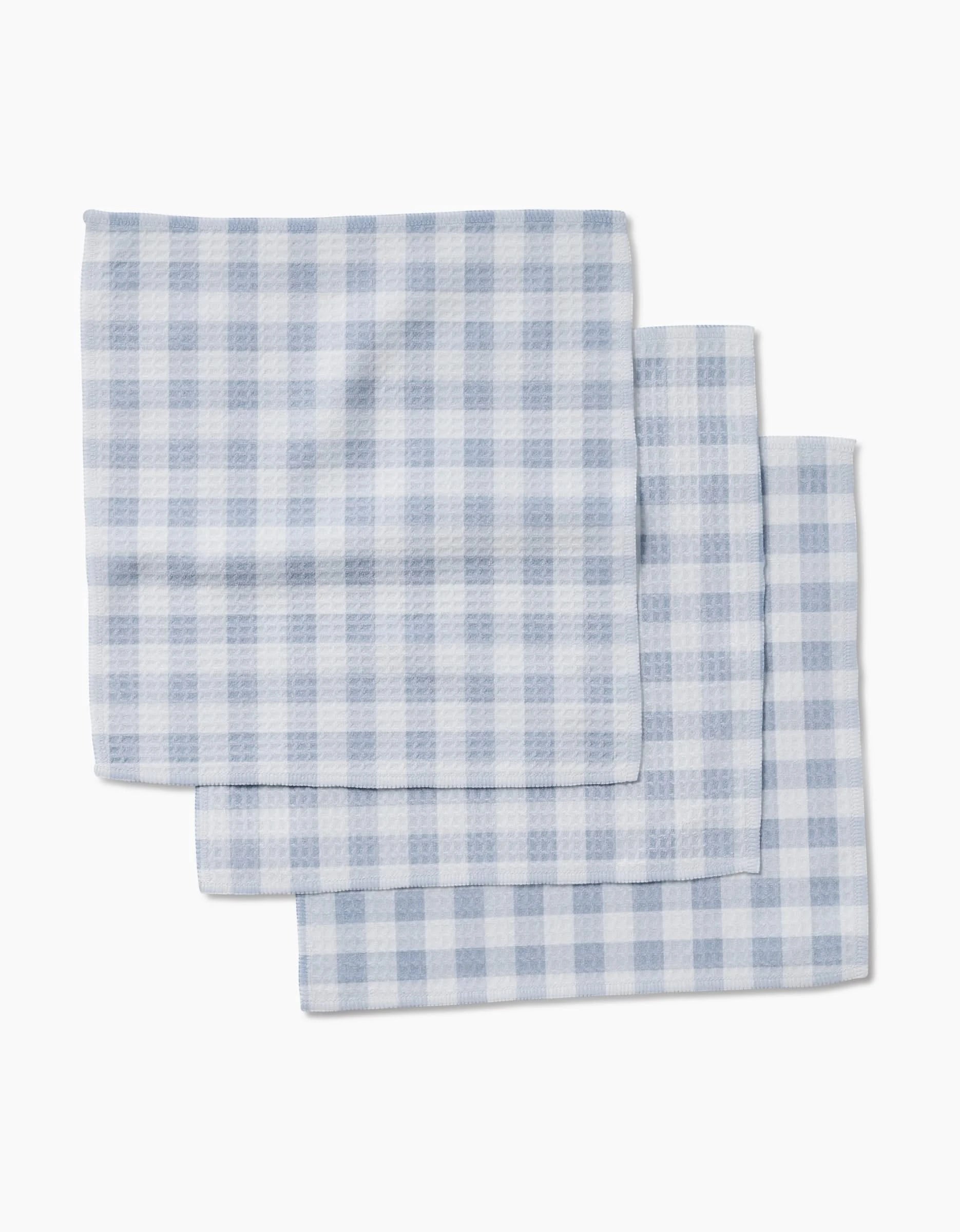 Three Blue Gingham cloth napkins by Aubrey Fairchild, featuring ultra-absorbent Geoweave technology, are neatly stacked and slightly overlapping against a white background.