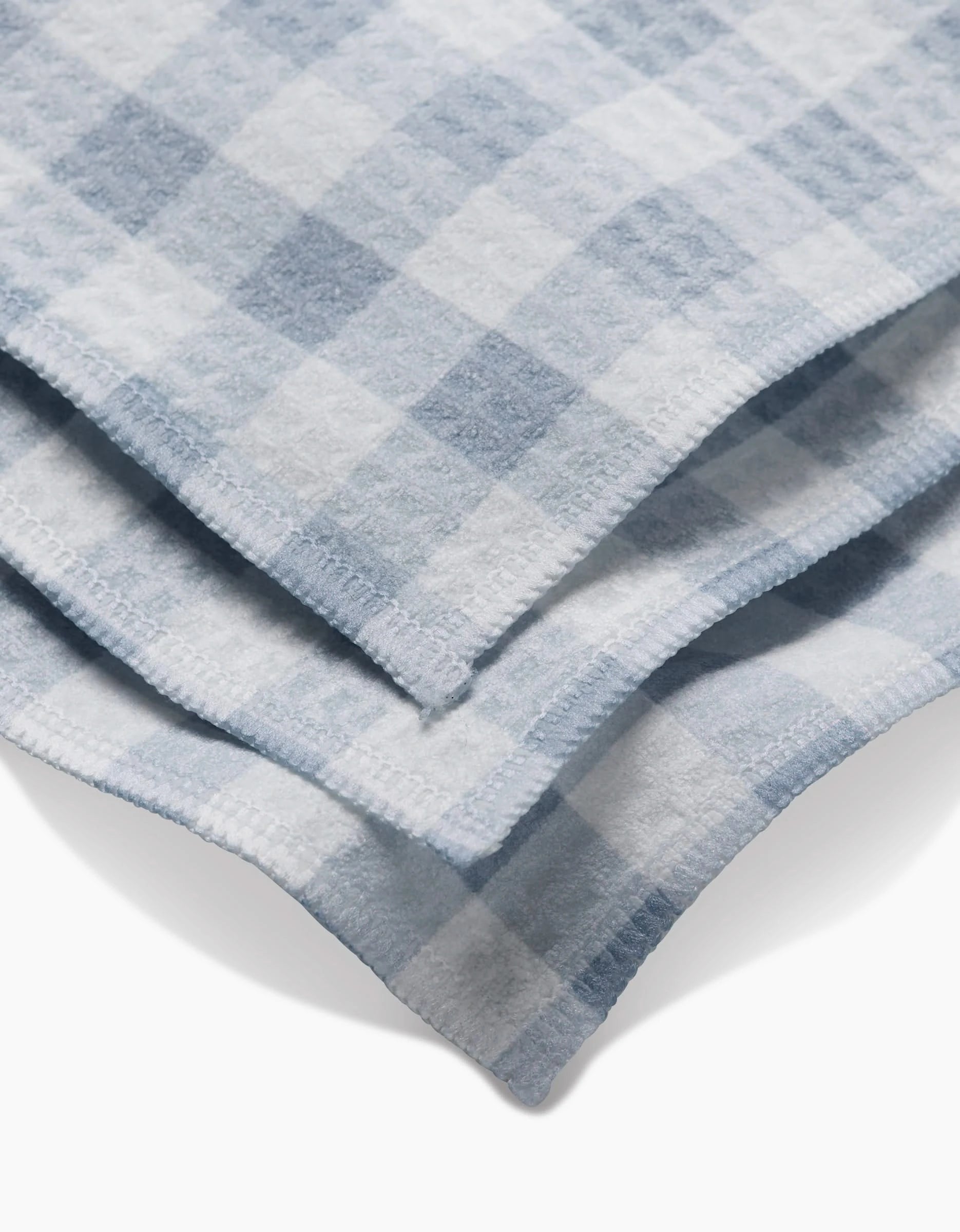 A close-up of the Aubrey Fairchild Blue Gingham washcloths, featuring soft light blue and white checks with visible edge stitching, highlights their ultra-absorbent Geoweave technology.
