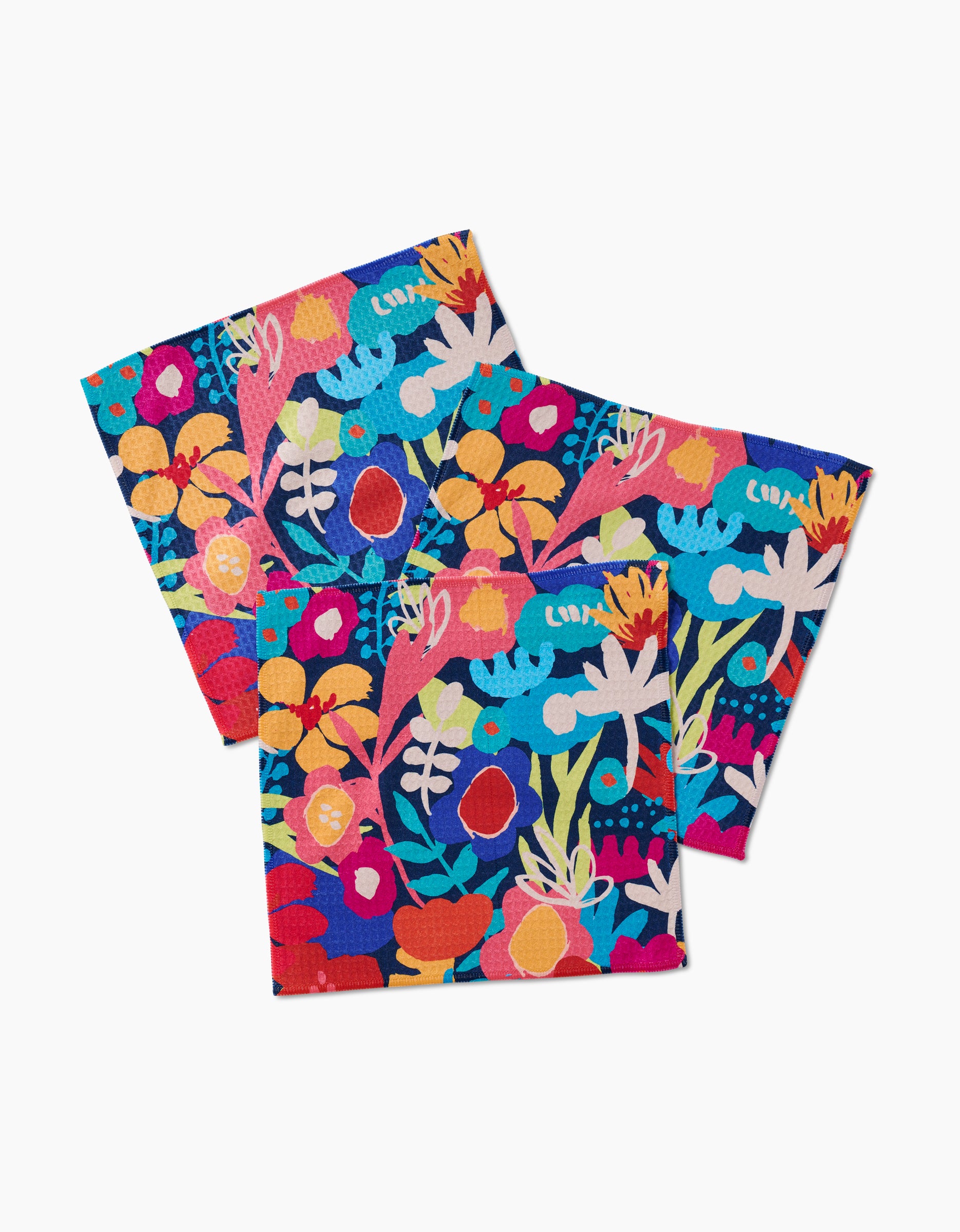 Three Bright Bunch square napkins by Sareka Unique, featuring a vibrant floral pattern in red, yellow, blue, and pink on white, are crafted with ultra-absorbent Geoweave technology and shown overlapping.