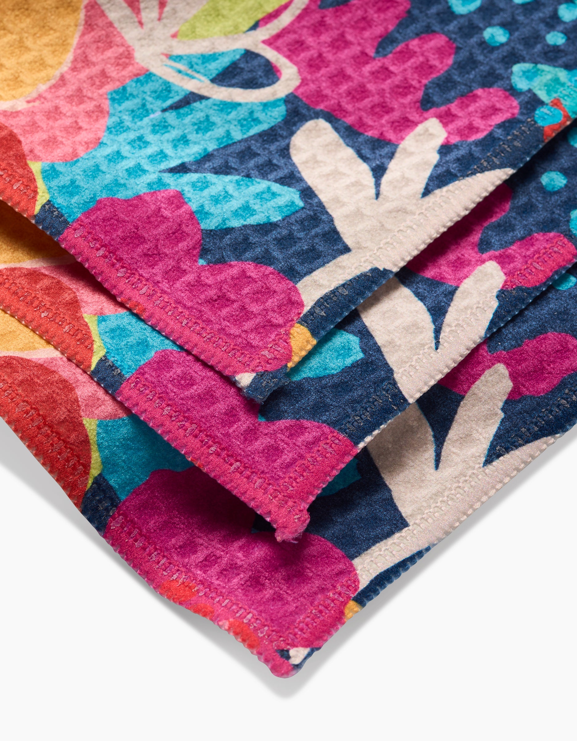 A close-up of folded Bright Bunch fabric by Sareka Unique, showing a colorful abstract floral pattern with visible stitching—crafted from ultra-absorbent Luxe Washcloth material.