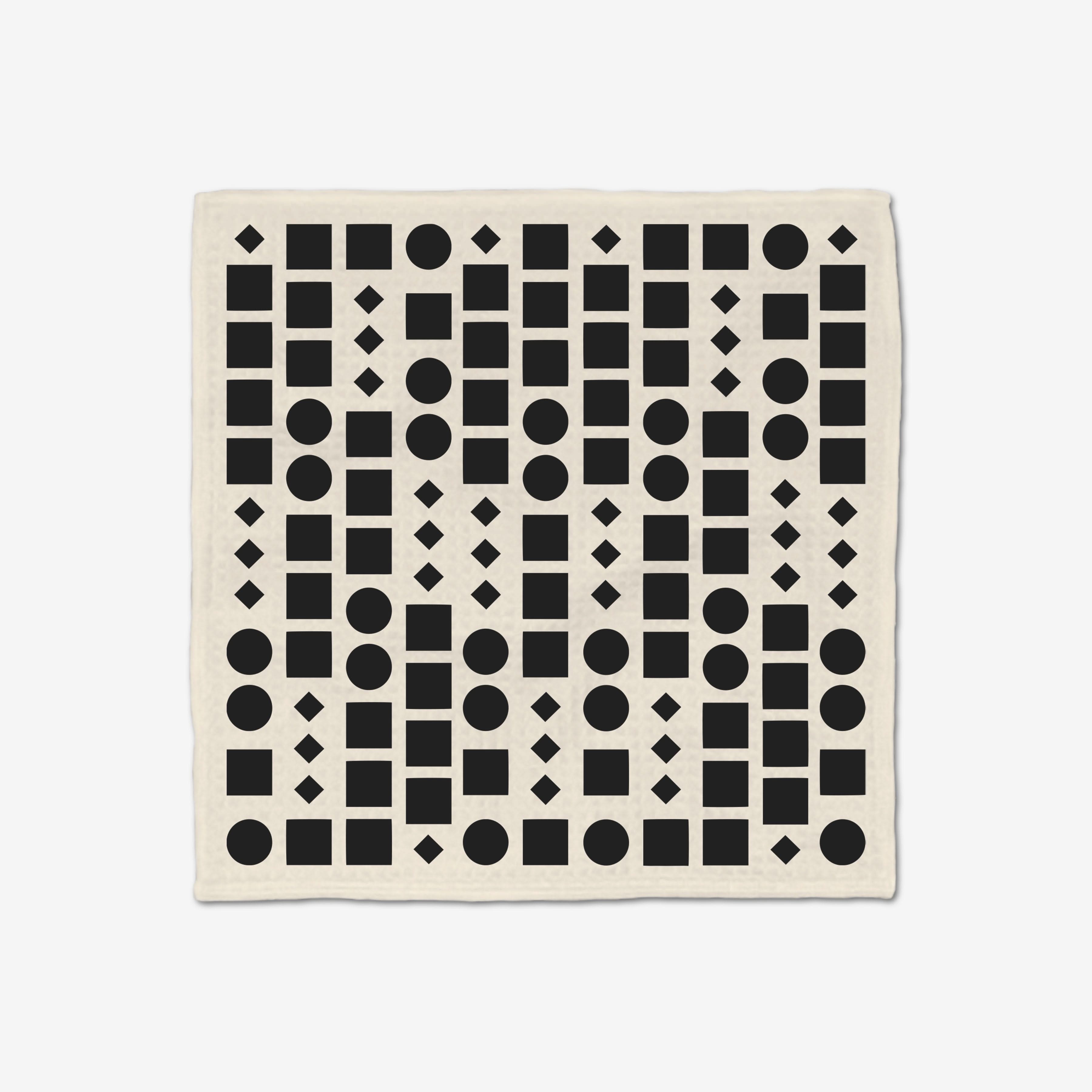 The GEOMETRY Coded Luxe Washcloth is cream-colored and made from post-consumer recycled materials. It features a repeating grid of black circles, squares, and diamonds. Ultra-absorbent and stylish for everyday use.