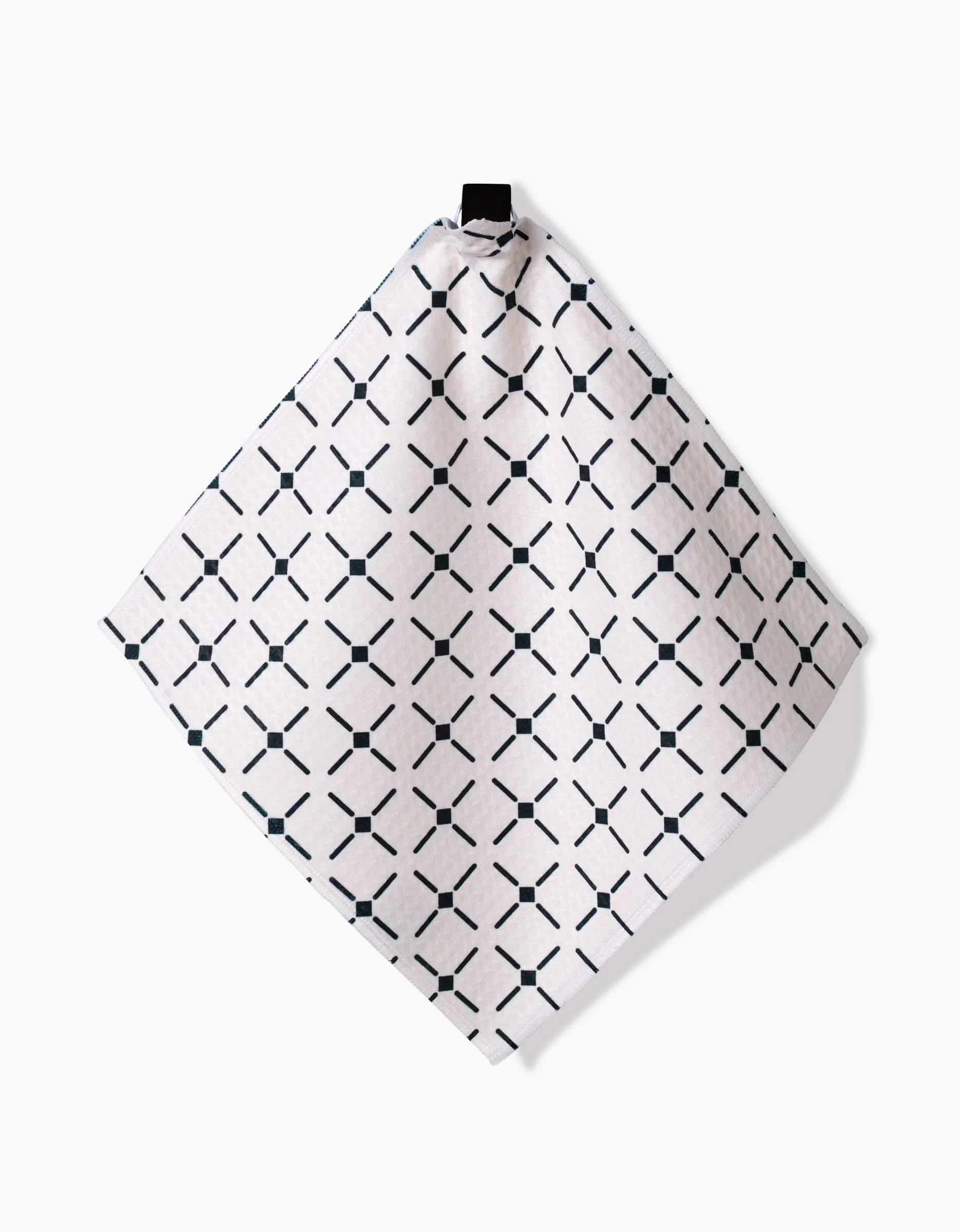 The Collins napkin by Charlie Rowan Designs features a black geometric diamond and dot pattern on white, hanging from a loop against a plain background—crafted with Geoweave technology for superior absorbency.