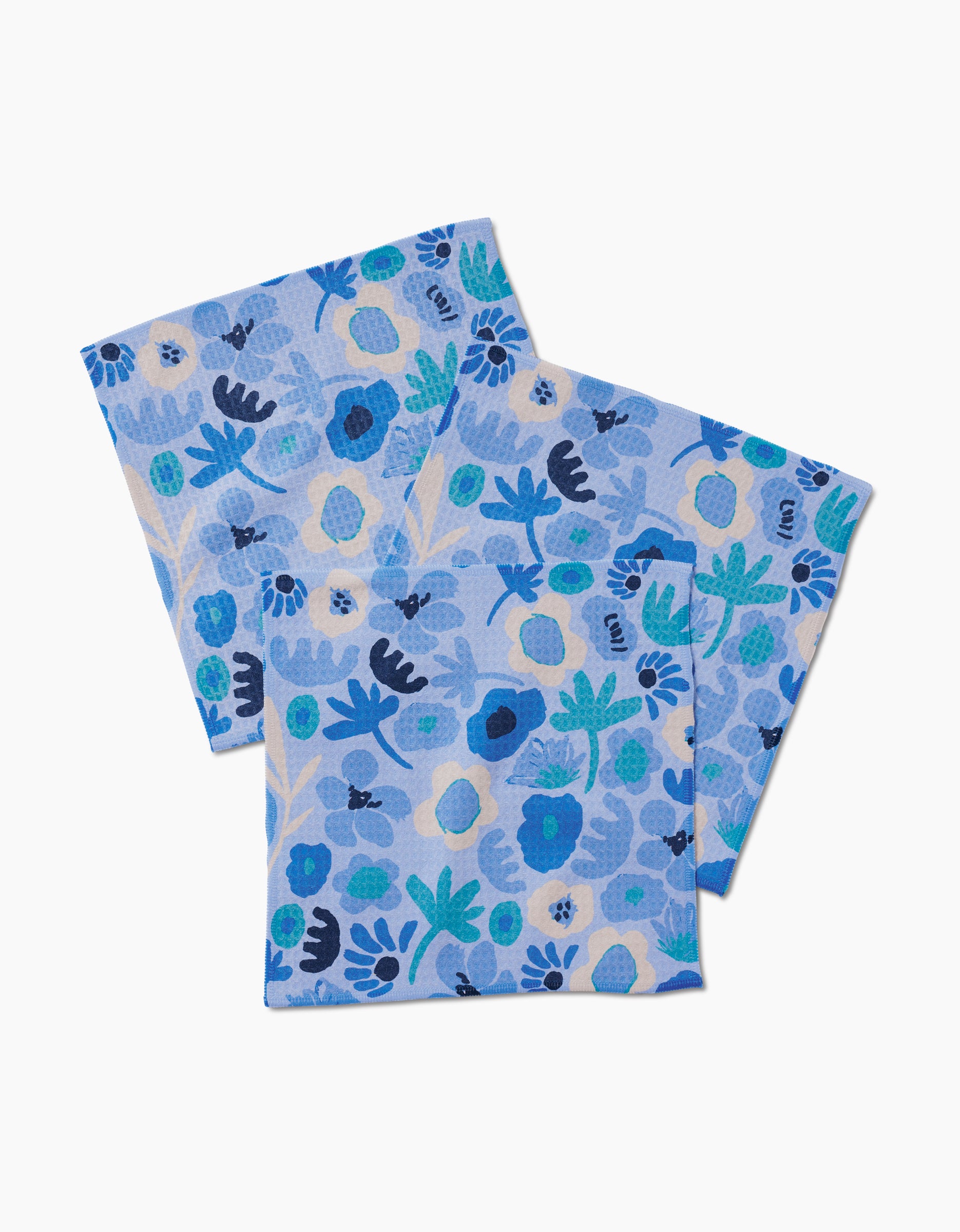 Two Cool Blooms napkins by Sareka Unique in blue cotton, featuring a blue, teal, and white floral pattern. Overlapping on a white background. Made with ultra-absorbent Geoweave technology for beauty and function.