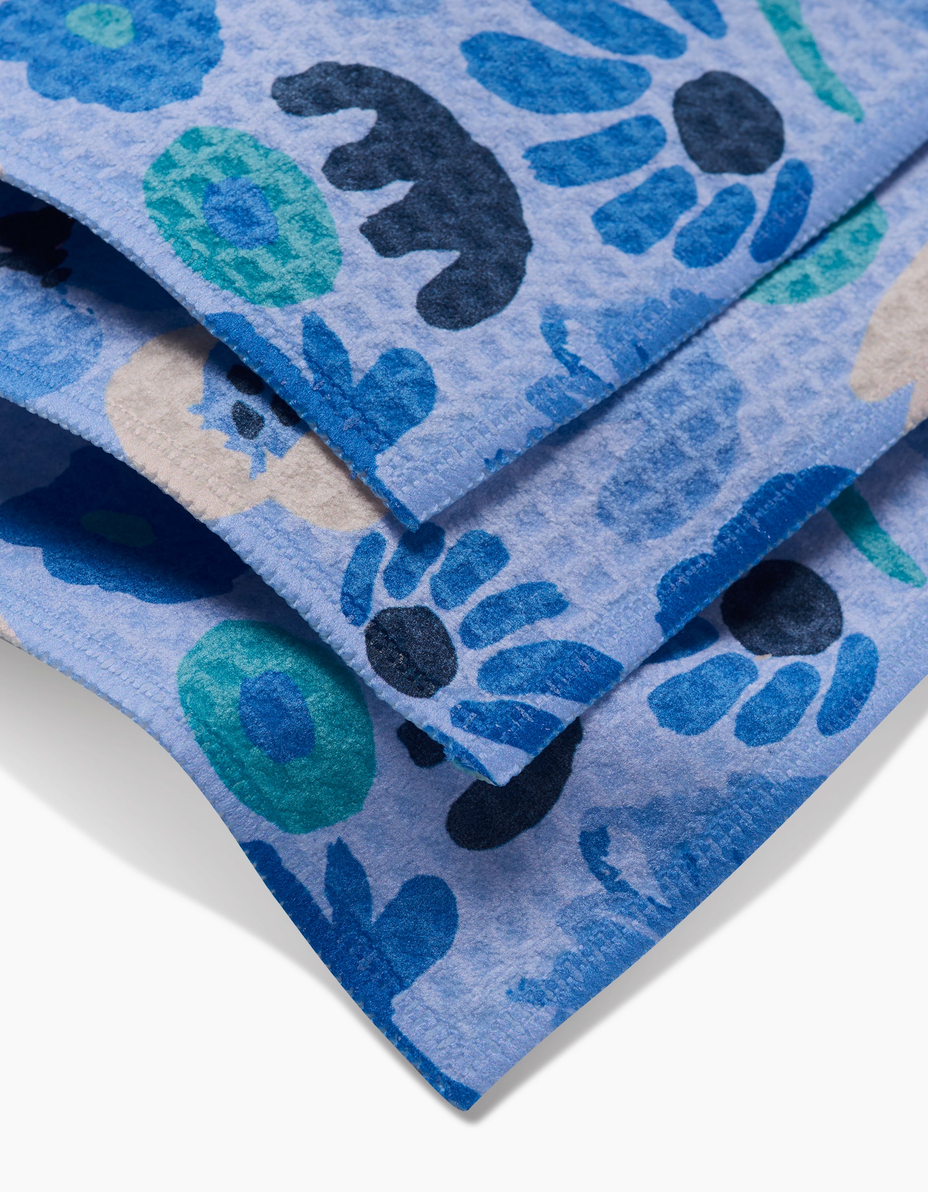 Close-up of folded blue Sareka Unique Cool Blooms washcloths featuring playful animal and floral prints in blue tones on a light background, crafted with ultra-absorbent Geoweave technology.