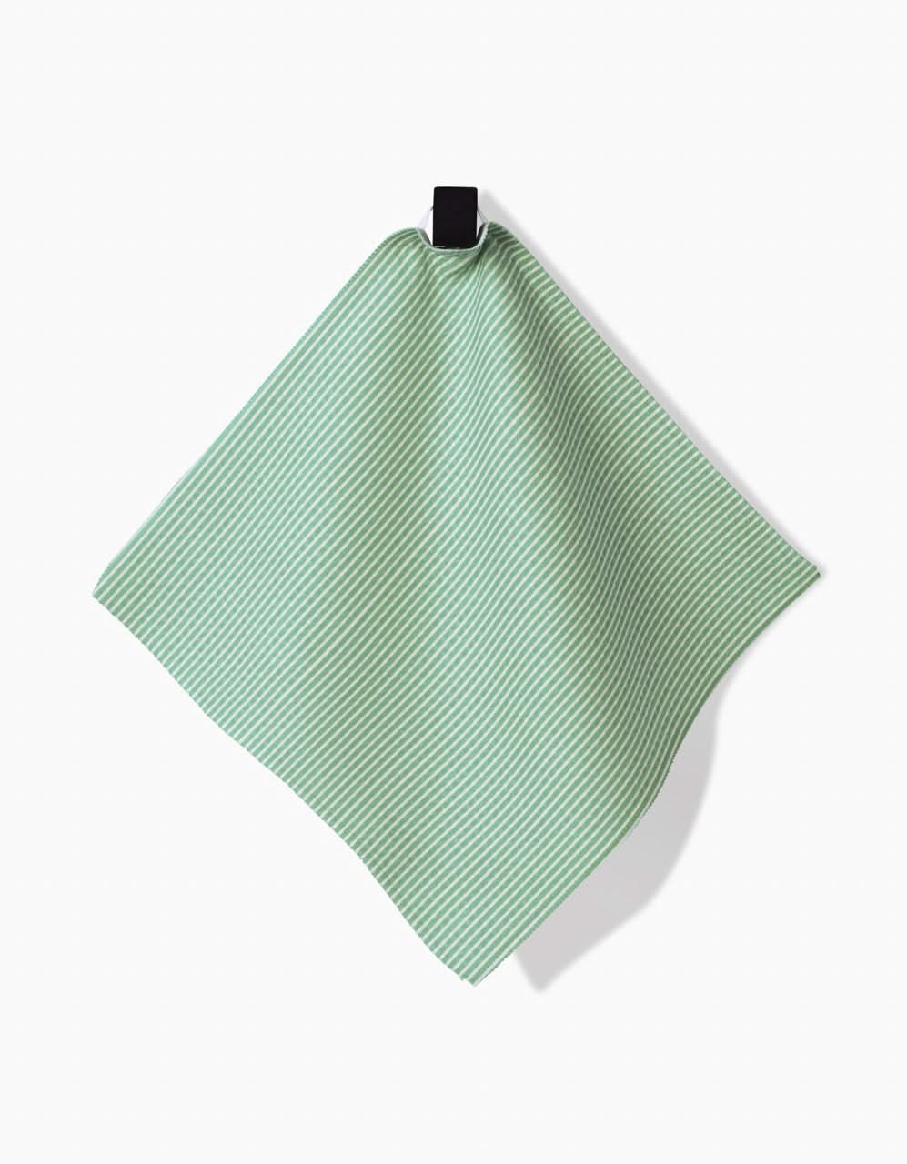 A green and white striped GEOMETRY Half and Half washcloth hangs from a black loop against a white background, featuring ultra-absorbent Geoweave technology.
