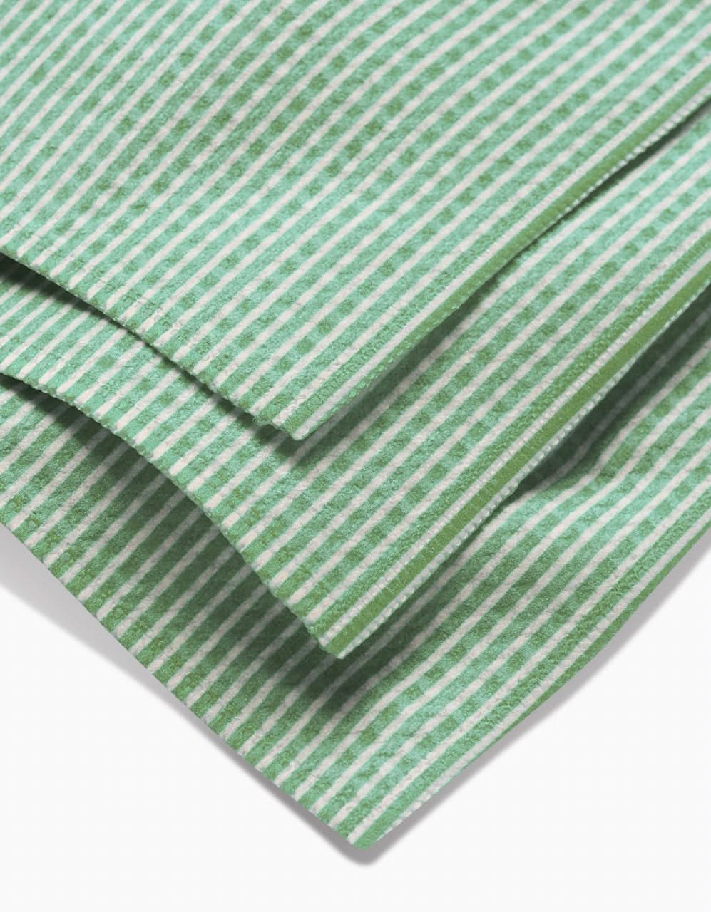Close-up of folded GEOMETRY Half and Half Luxe Washcloth, featuring a green and white striped pattern with ultra-absorbent Geoweave technology. Three diagonal layers overlap on a white background.