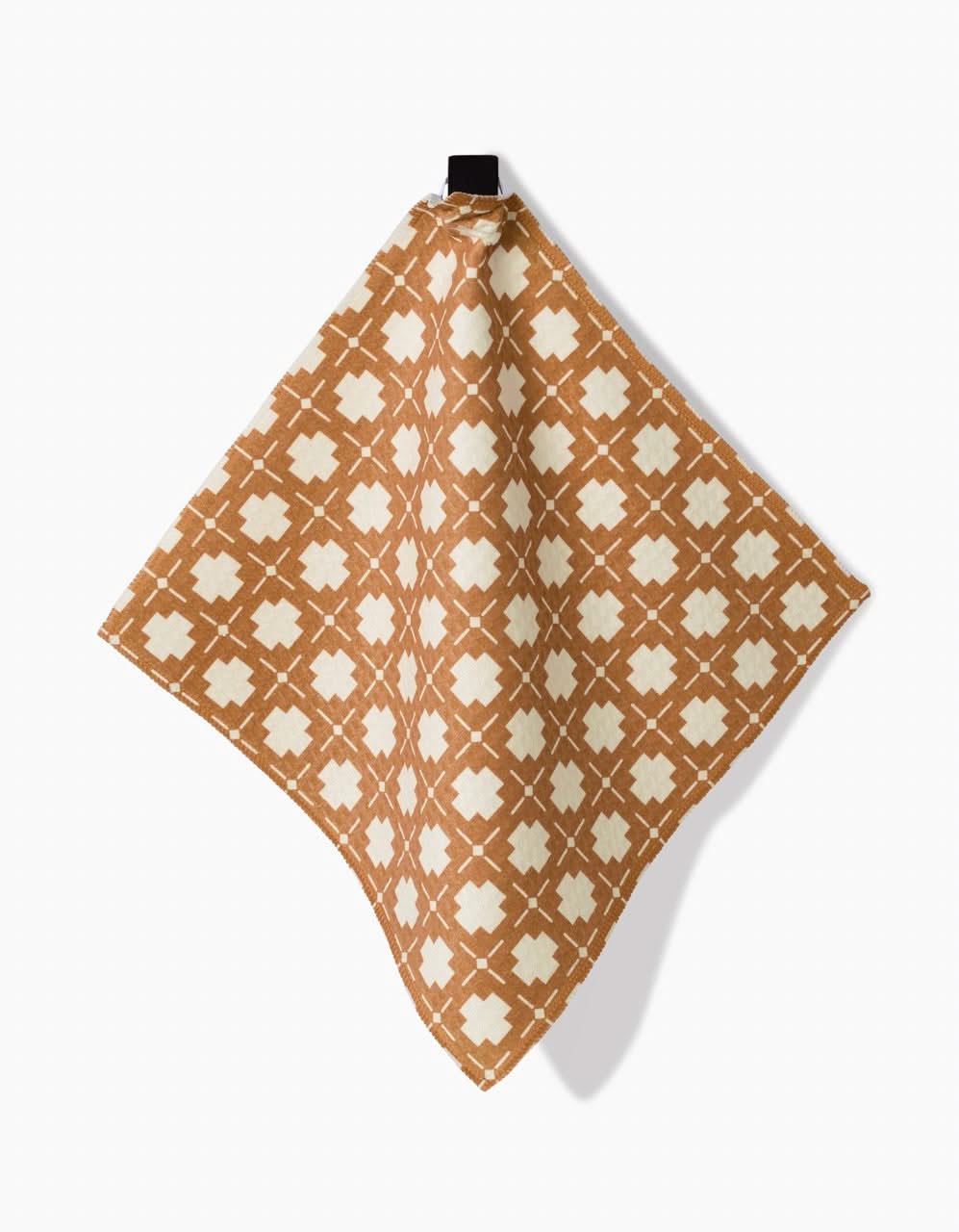 The Jackson washcloth by Charlie Rowan Designs features a brown base with a cream geometric pattern, made from recycled materials. It hangs from a small black loop against a white background.