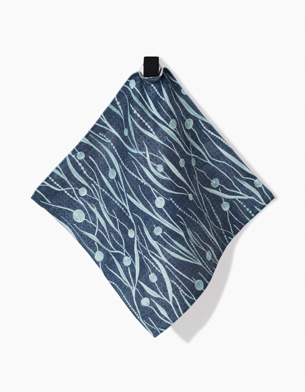 The Kelp cloth napkin by Katie OShea features light blue abstract lines and dots, ultra-absorbent Geoweave tech, and hangs by a black loop against a white background.
