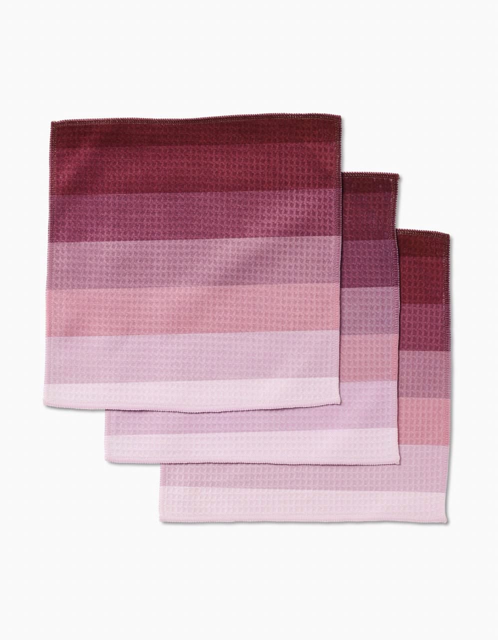Three Mauve Levels cloth napkins by GEOMETRY, stacked to show horizontal stripes in pink, mauve, and burgundy. Made with ultra-absorbent Geoweave technology and displayed on a white background.