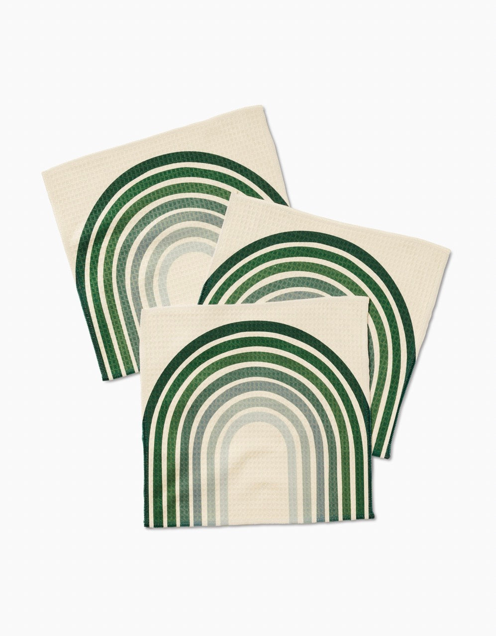 Three cream-colored GEOMETRY Olive Arches Luxe Washcloths, featuring green and teal arch designs with ultra-absorbent Geoweave technology, are arranged in an overlapping pattern on a white background.