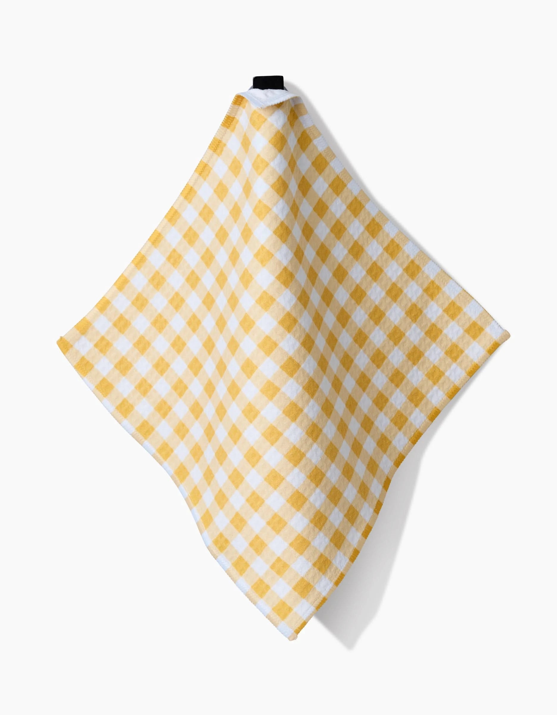 The Spring Morning dish towel by Danelys Sidron features a yellow and white checkered pattern, crafted with ultra-absorbent Geoweave technology. Draped in a diamond shape, it hangs by its black loop against a white background.