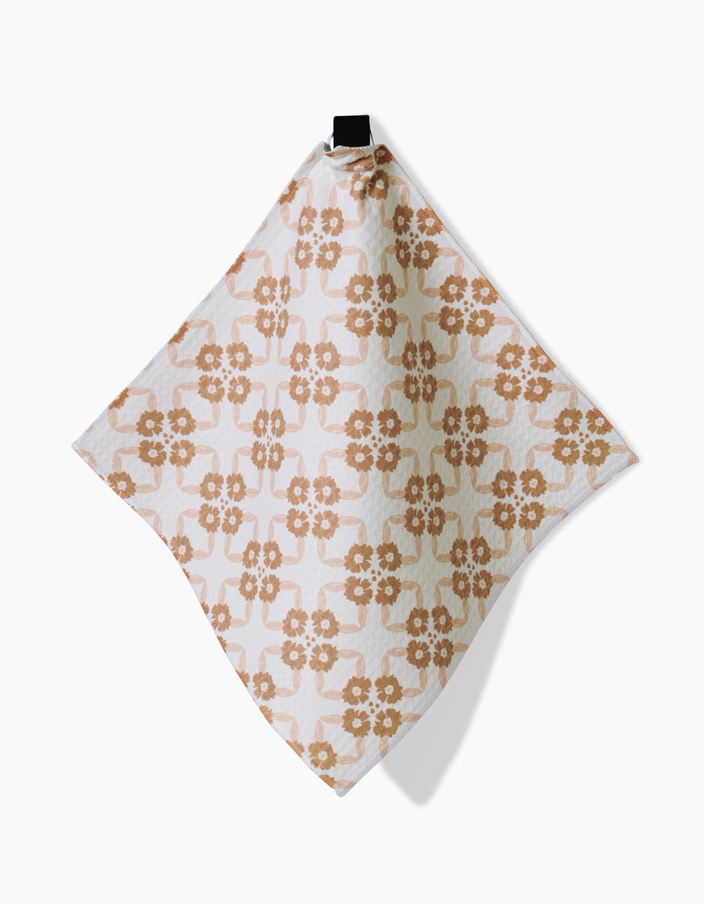 The Sweet Boho washcloth by Hufton Studio, featuring a tan and white floral geometric pattern, hangs from a black hook on a white background. Its crafted from ultra-absorbent recycled materials.