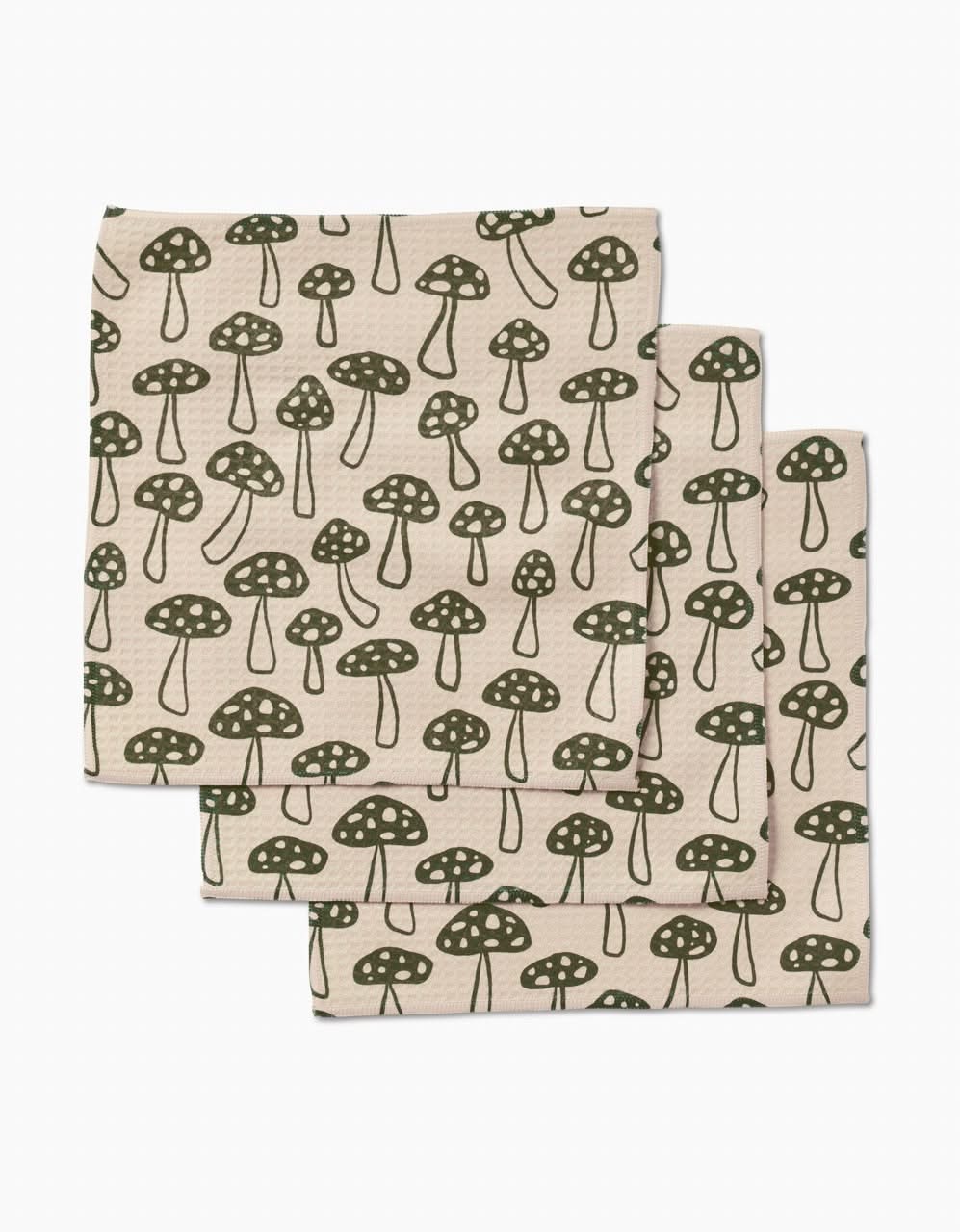 Three ultra-absorbent Kayla Ann Woodland Mushroom washcloths, crafted from post-consumer recycled materials and featuring a repeating green mushroom pattern, are neatly stacked with partial overlap on a white background.