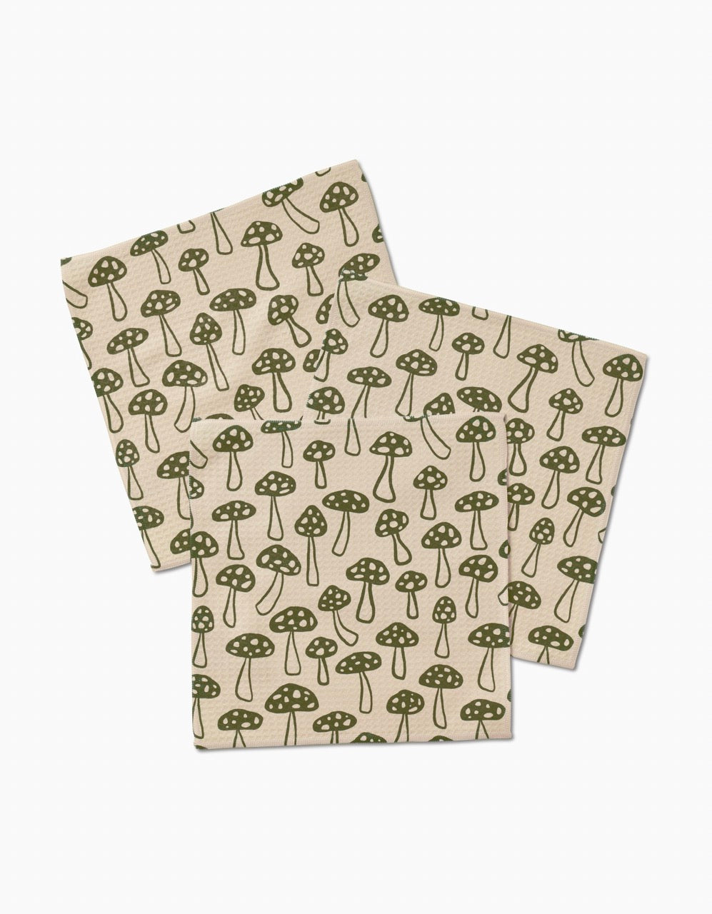 Three Kayla Ann Woodland Mushroom beige napkins, featuring a repeating green mushroom pattern with dotted stems and caps, are laid out slightly overlapping on a white background. Made from ultra-absorbent post-consumer recycled materials.